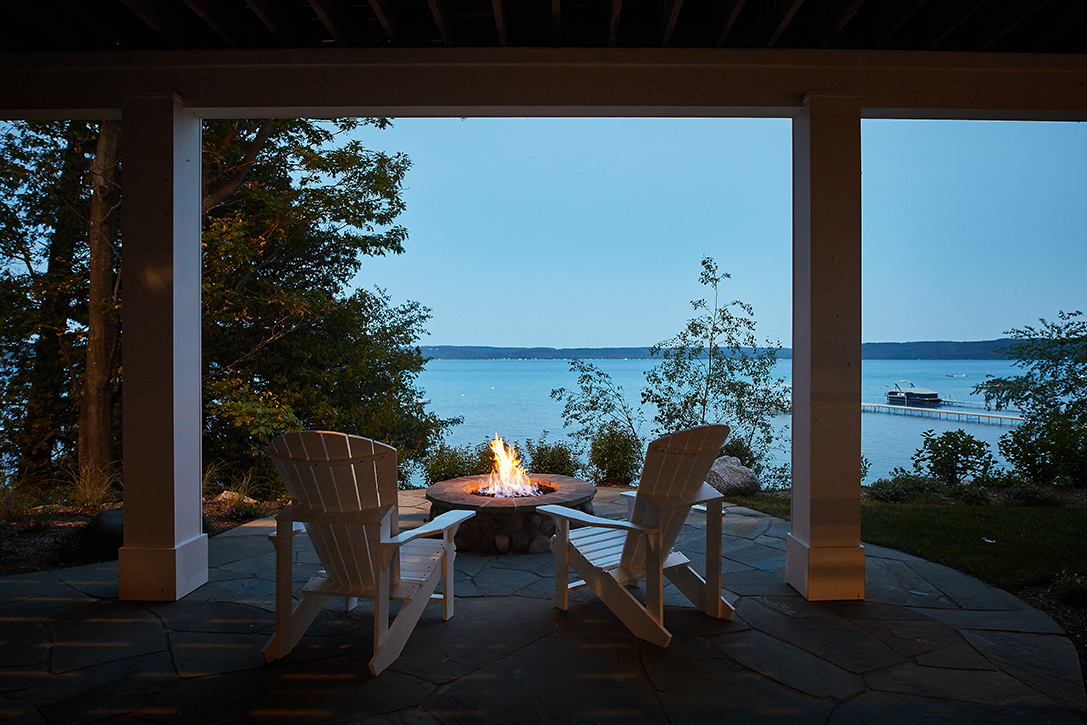 A beautiful lake front house with a fire at dusk