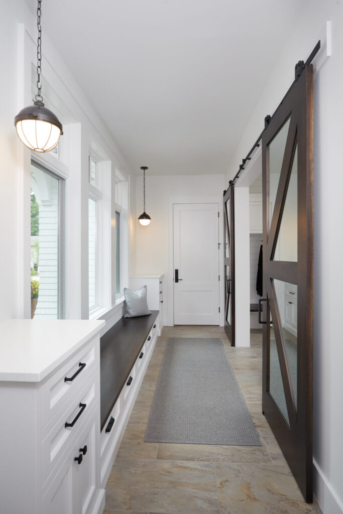Long mudroom hallway with bench and sliding barn door
