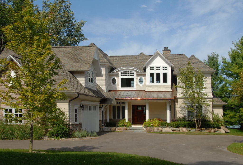 Front exterior of Cedar Bay cottage with covered entry, shingle siding, and curved driveway