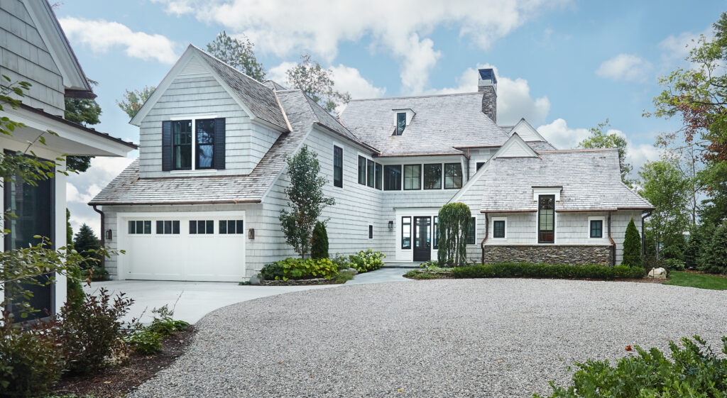 Lakeside home front elevation with gravel drive and shingle exterior