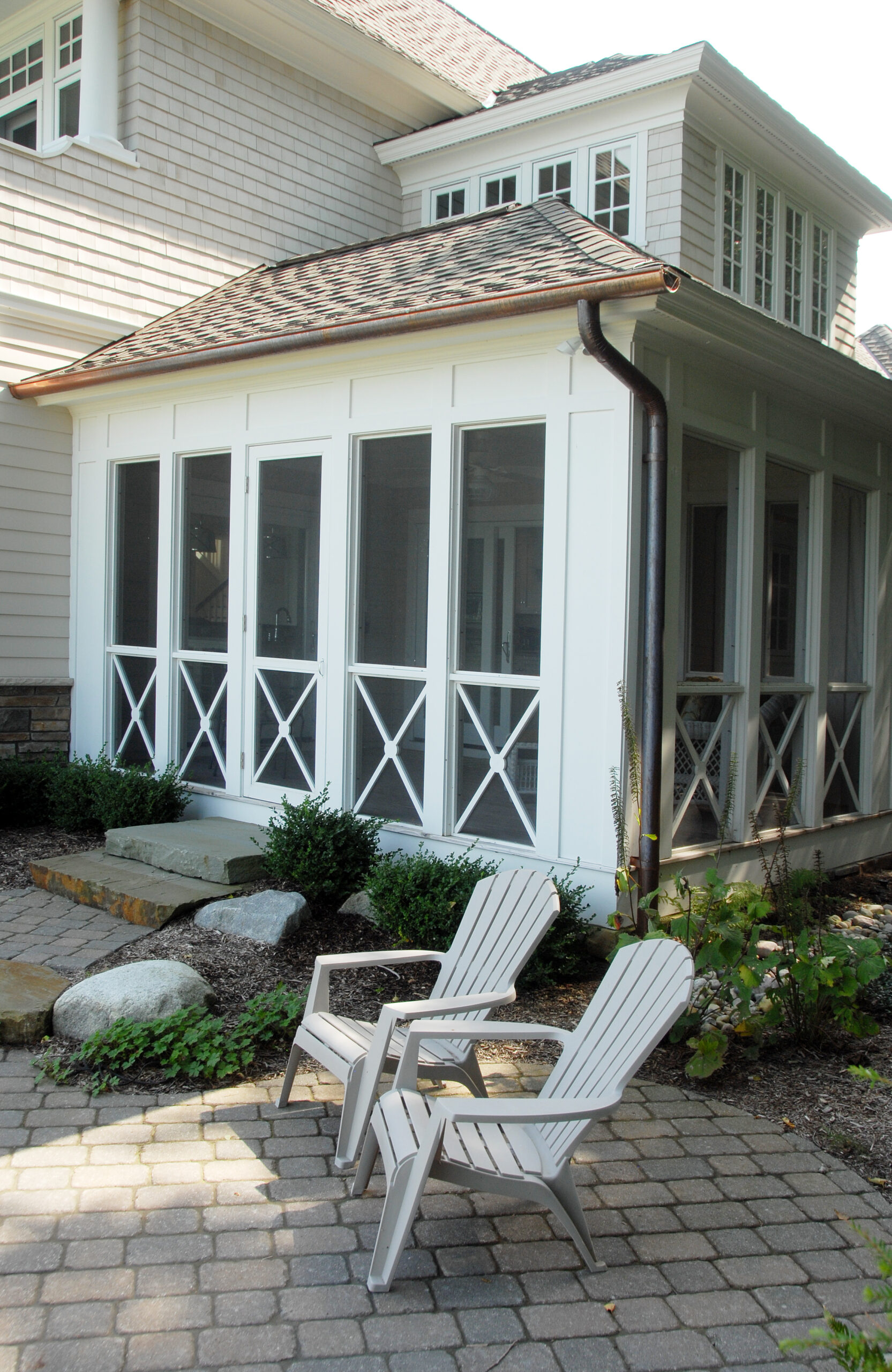 Screened porch with white trim and patio seating at lakeside cottage