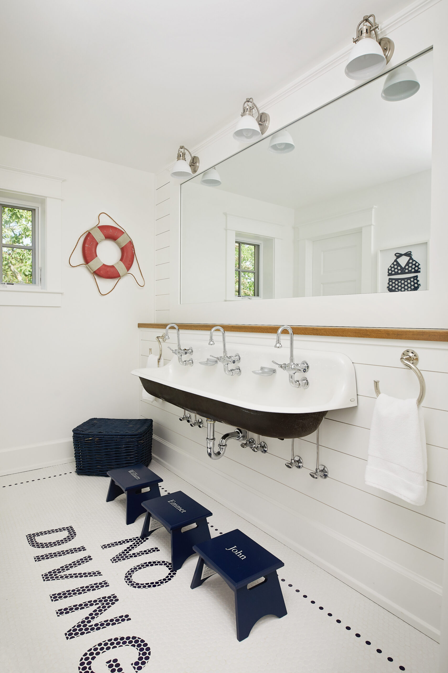 Kids bathroom with wall-mounted trough sink and personalized step stools