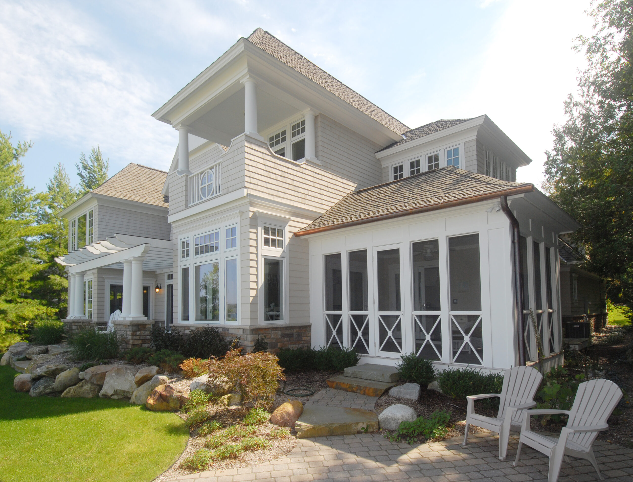 Lakeside cottage with shingle siding, screened porch, and upper balcony