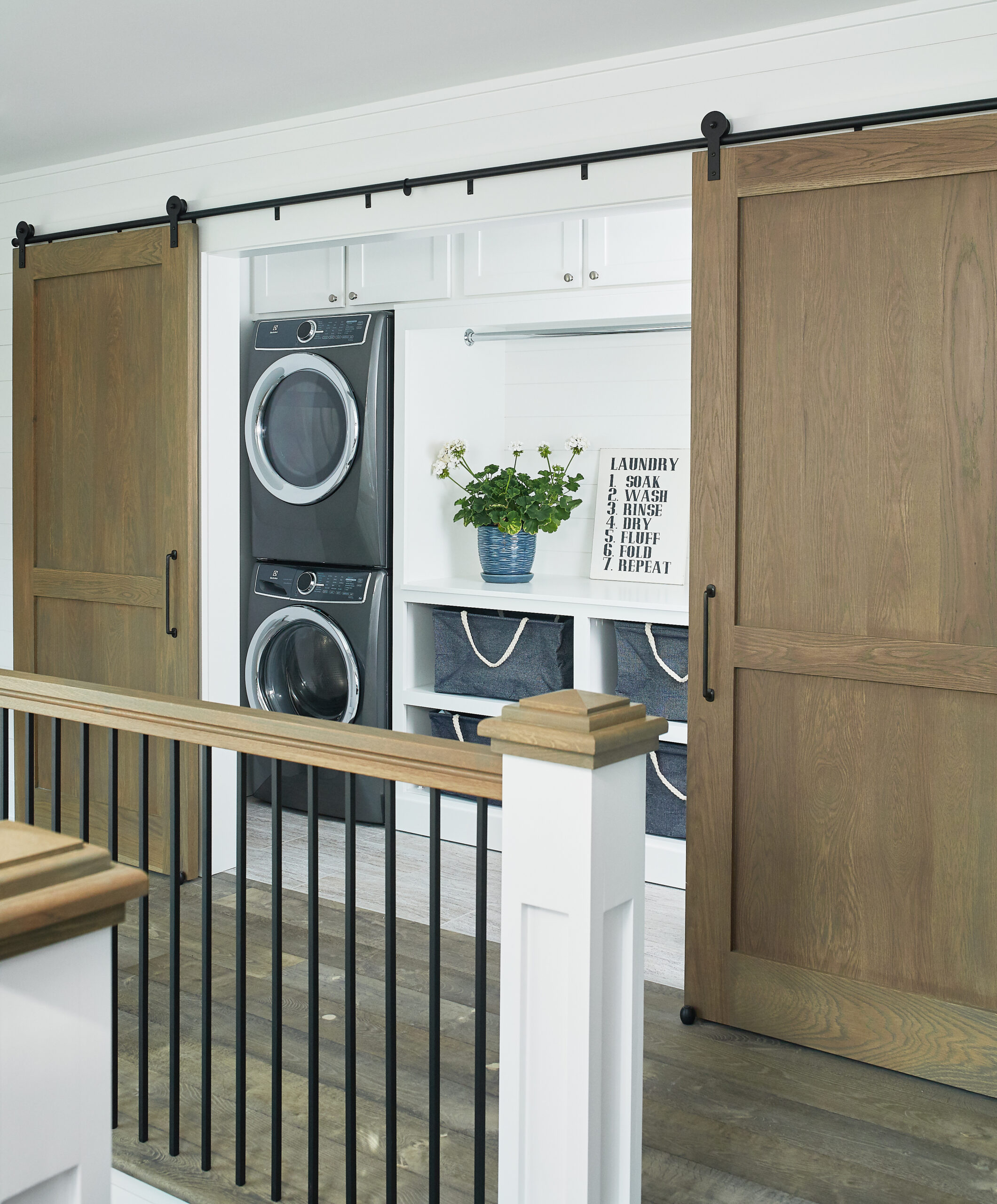 Upper-level laundry nook with sliding wood barn doors and stacked washer and dryer