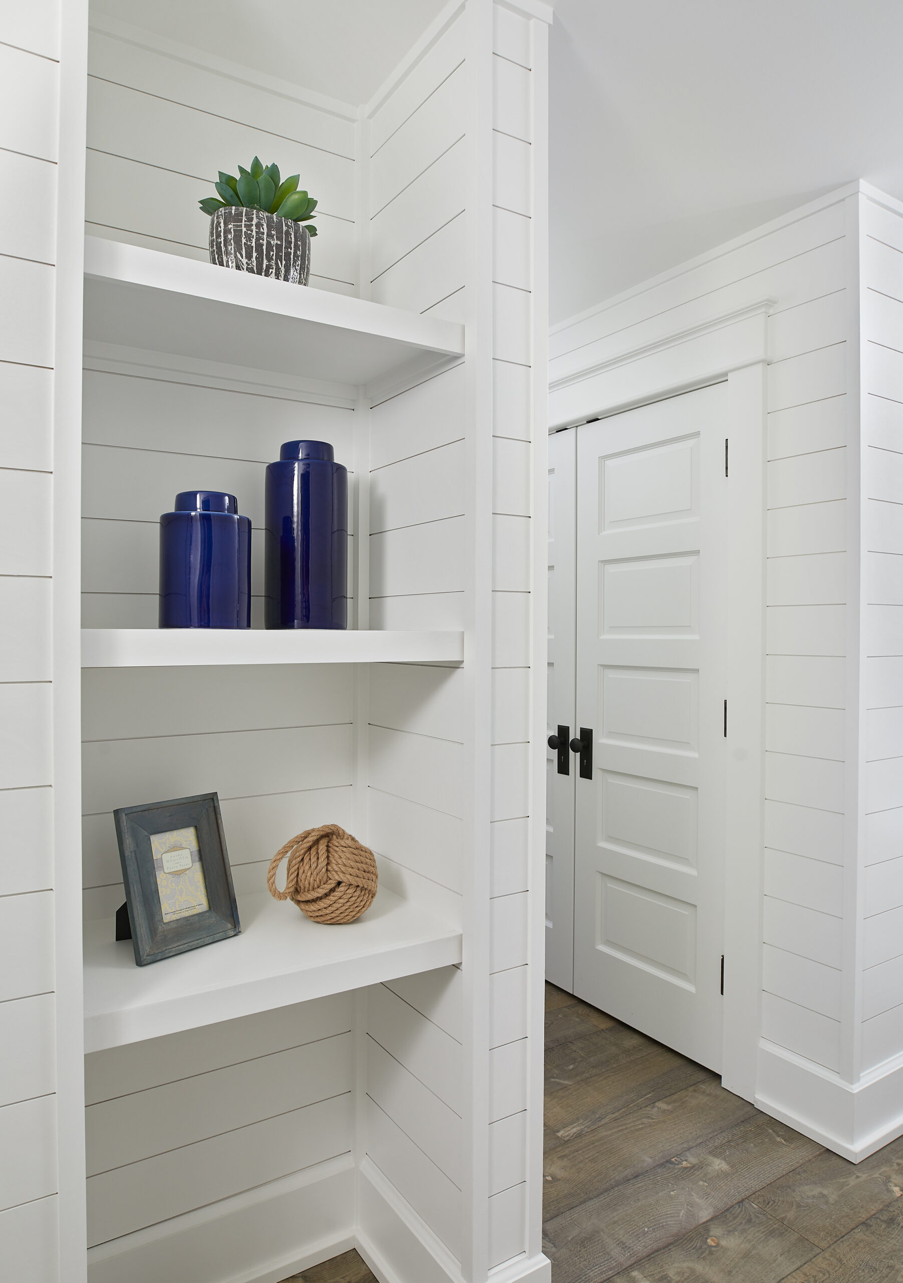 White shiplap hallway with built-in shelving and minimalist decor
