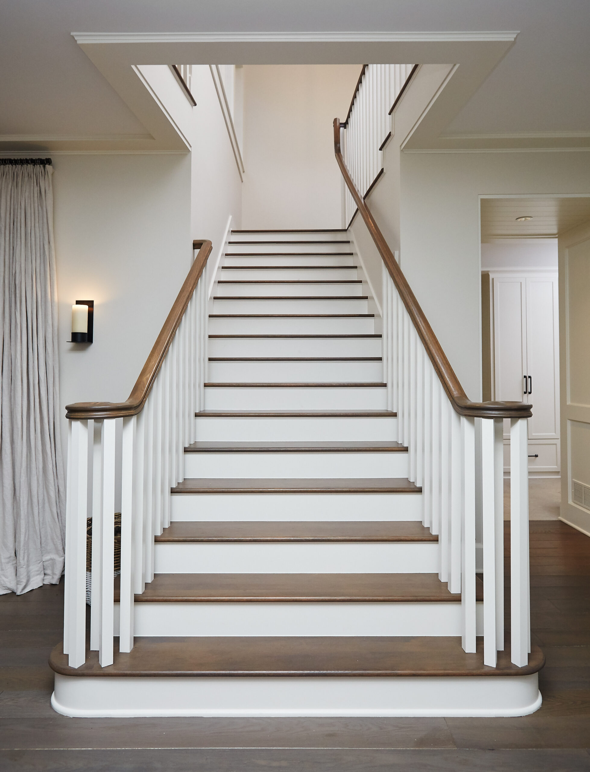 White staircase with wood treads, paneled railings, and curved wood handrails