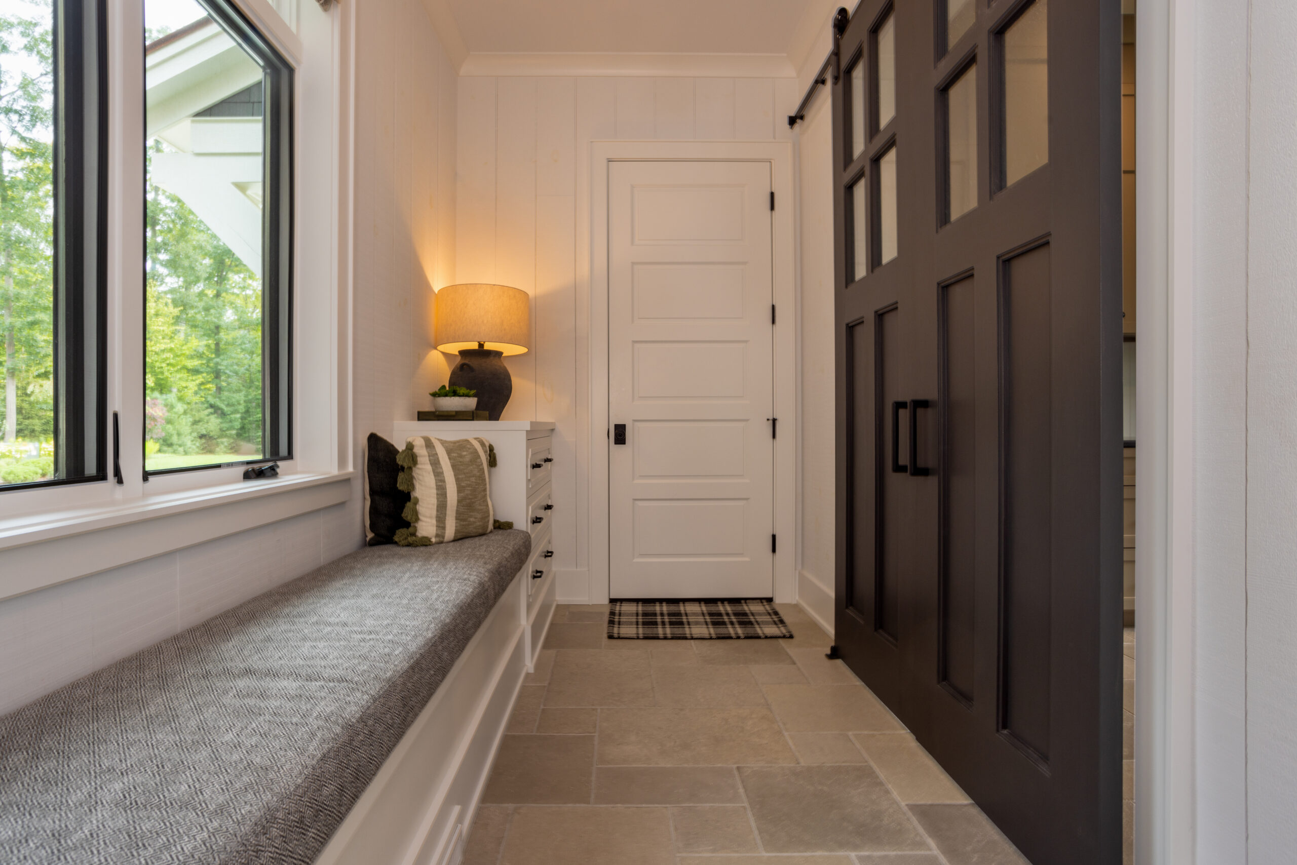 Mudroom with built-in bench, stone floor, and black barn doors.