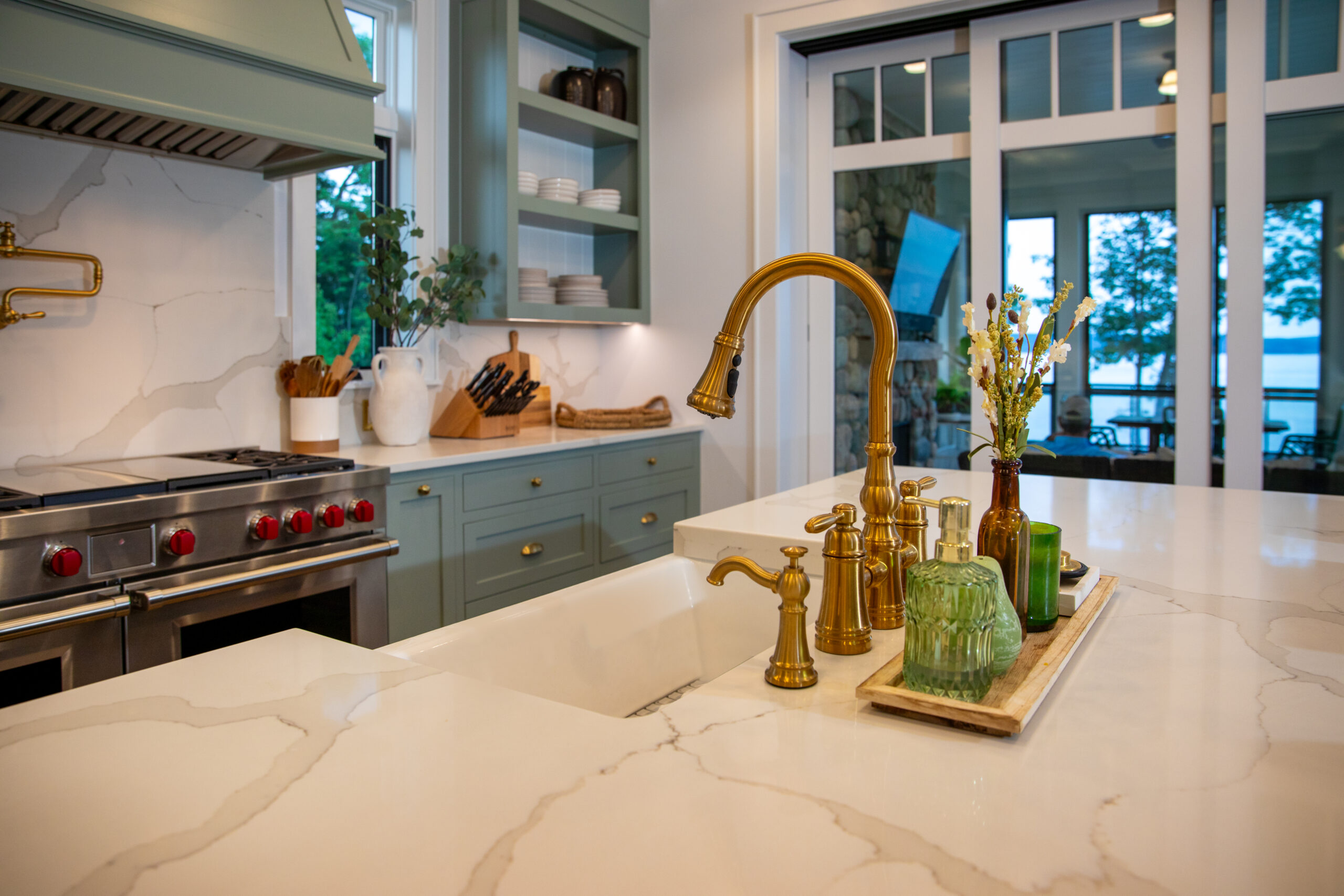 Close-up of kitchen sink with brass fixtures and marble countertops.