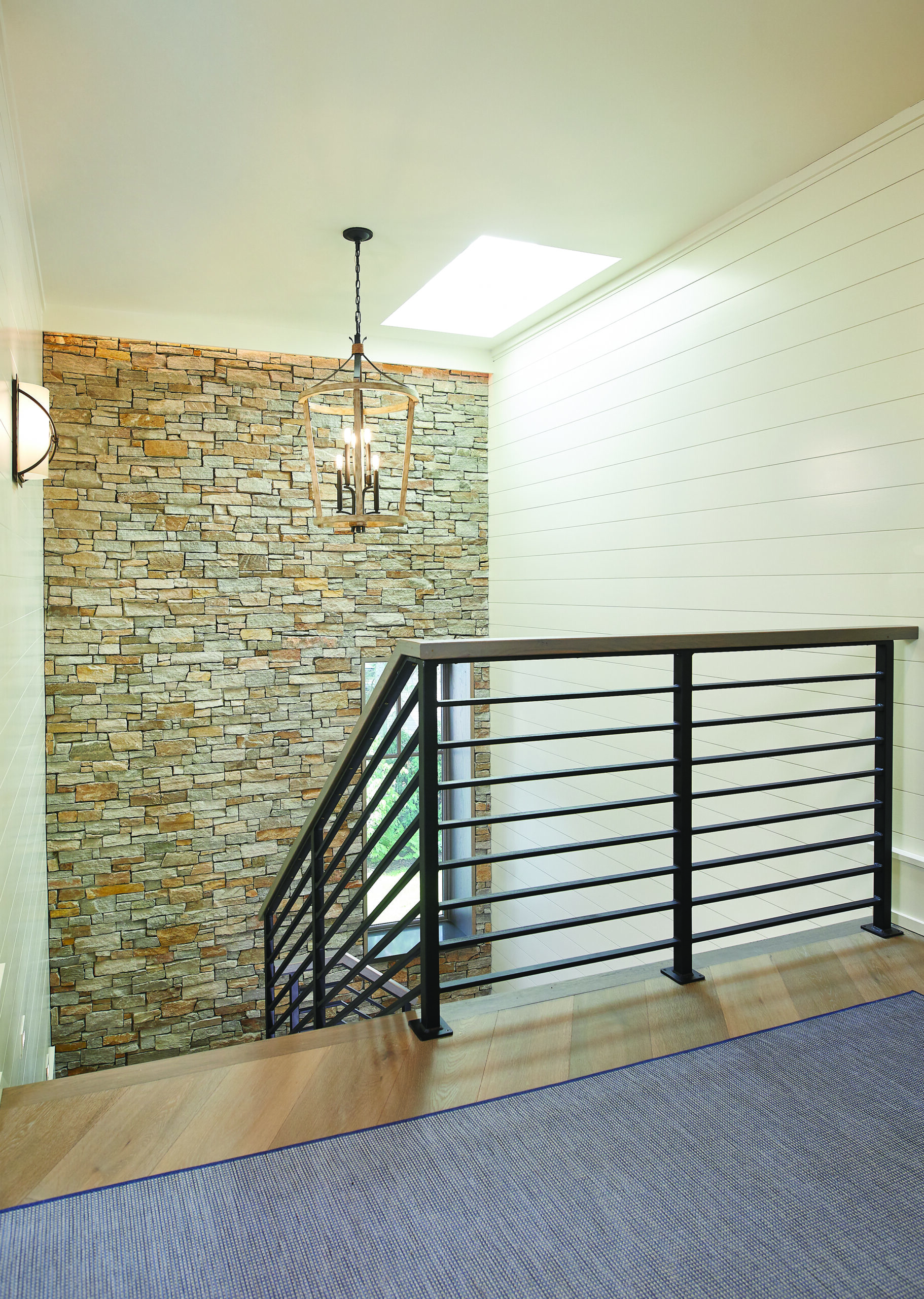 Modern stairway with stone accent wall and metal railing