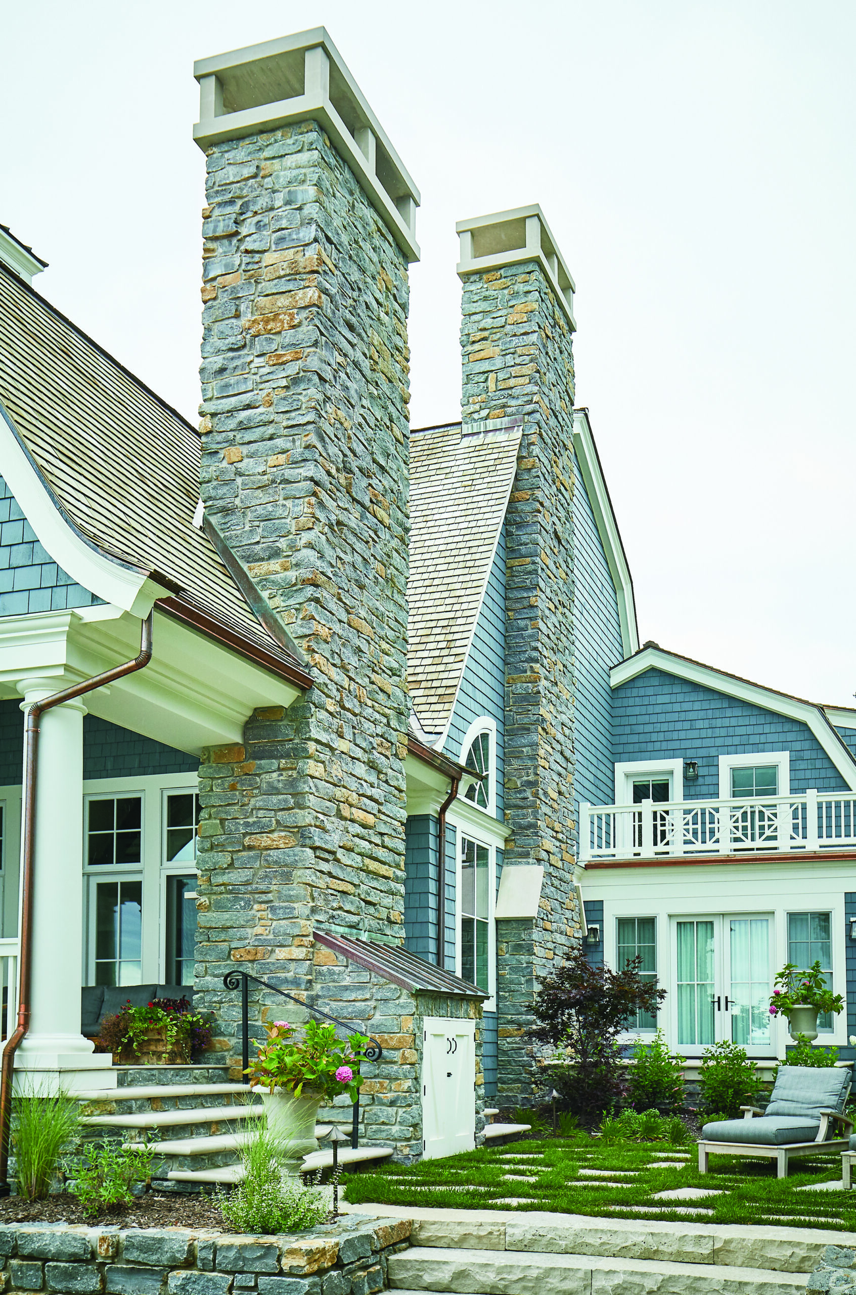 Glen Arbor lake home exterior with stone chimneys and blue shingle siding