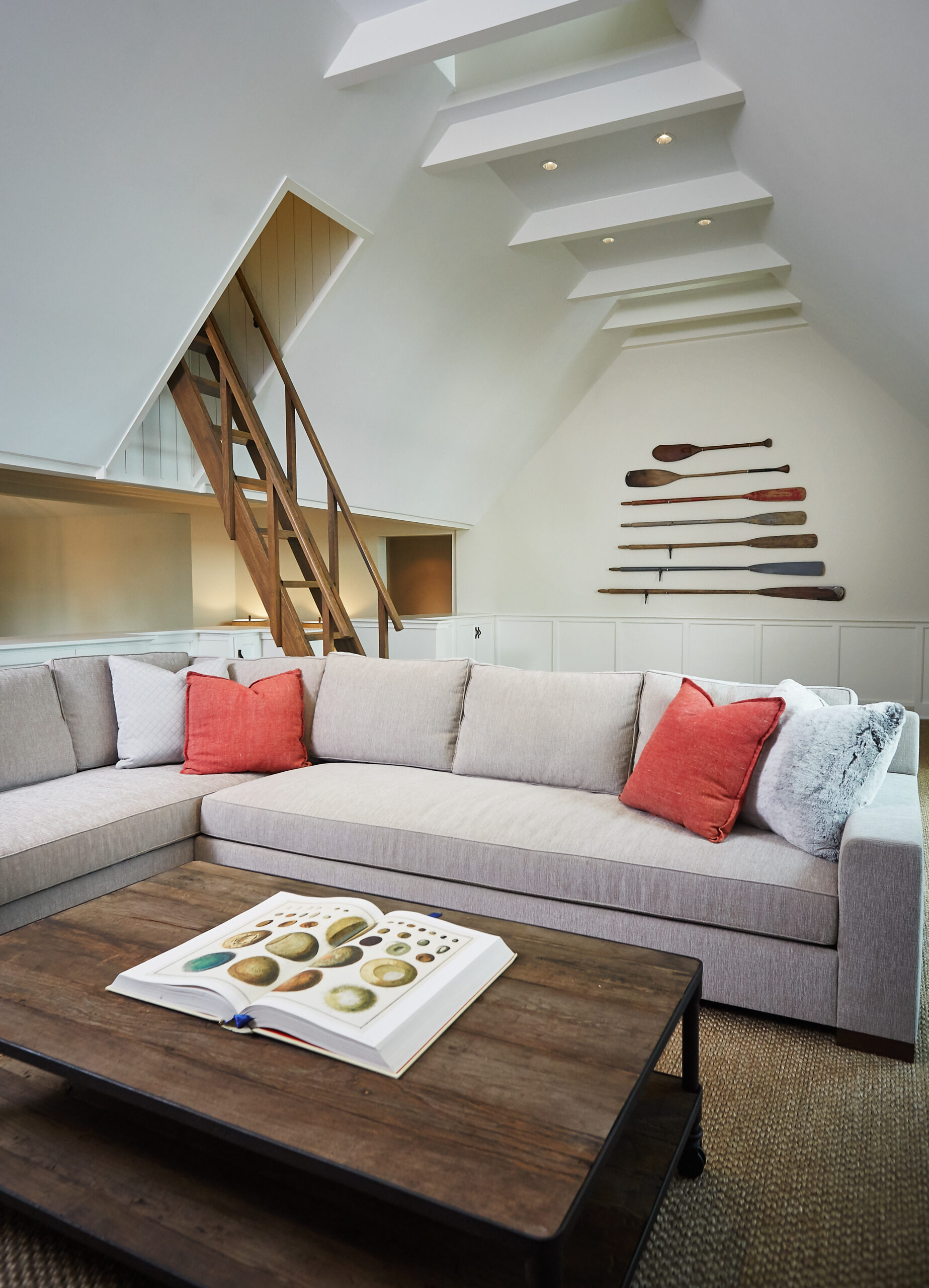 Loft-style lounge with custom ladder, white paneling, and exposed ceiling beams