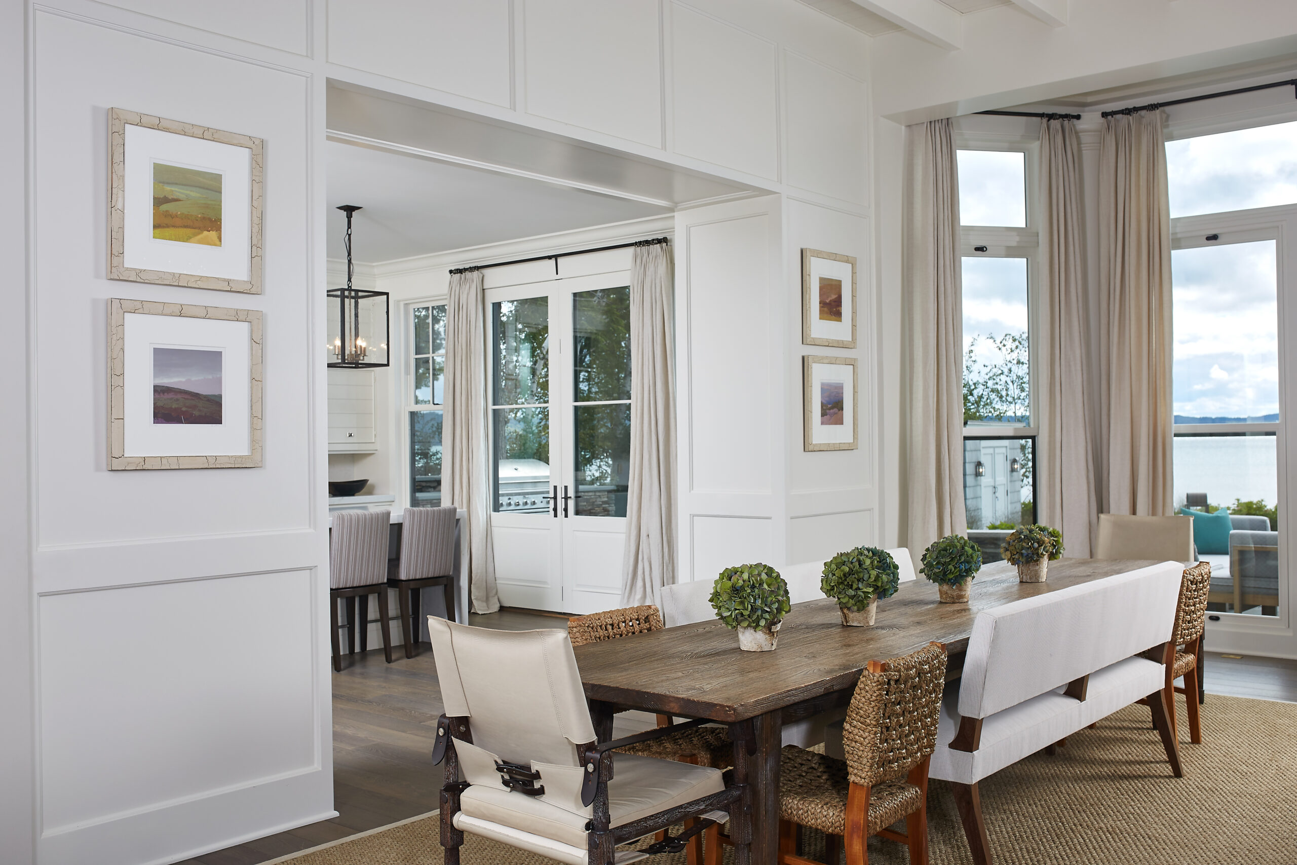 Bright dining room with custom white paneling, wood table, and lake-view windows