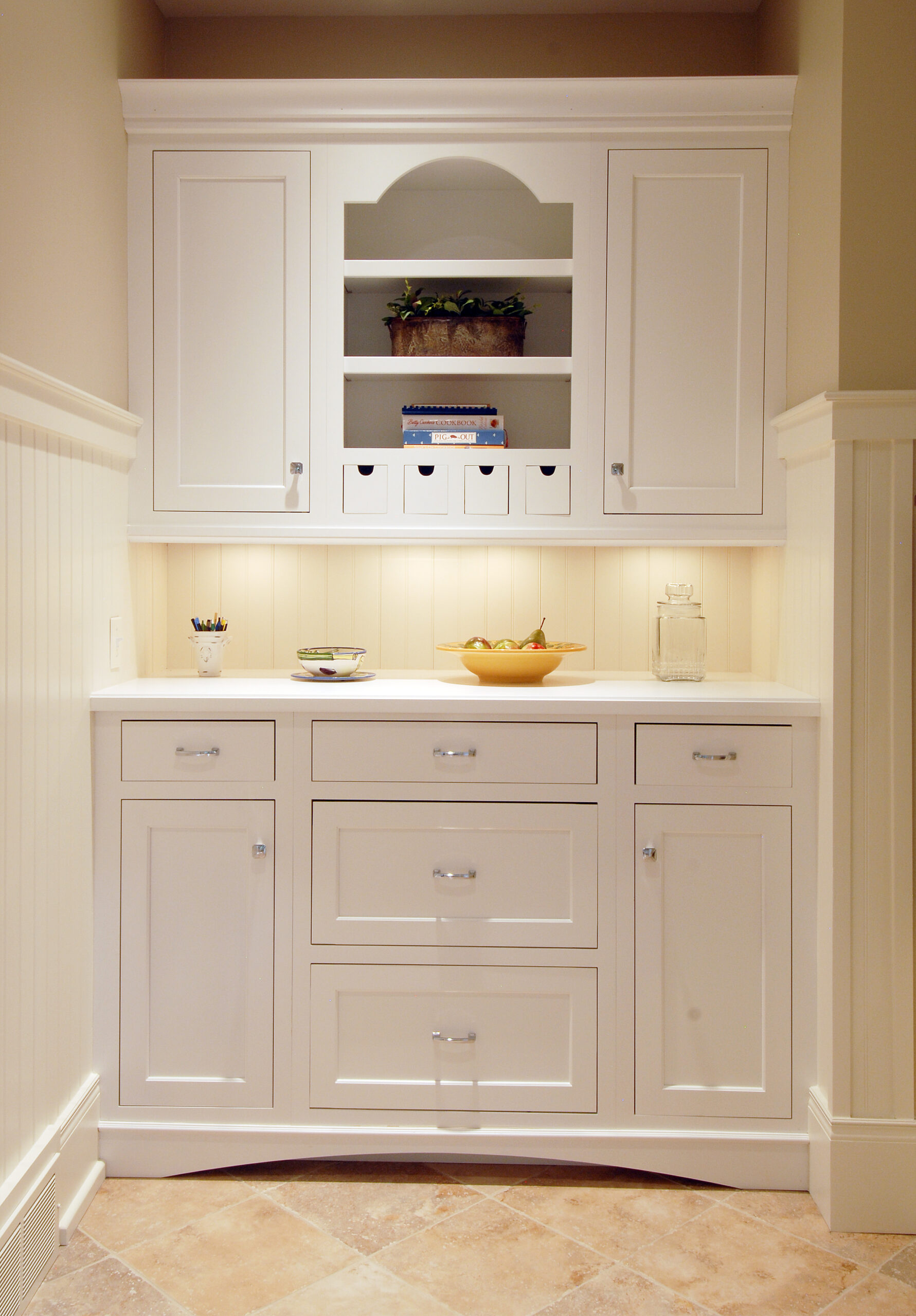 Built-in white cabinetry with drawers, shelving, and beadboard backsplash in a hallway nook