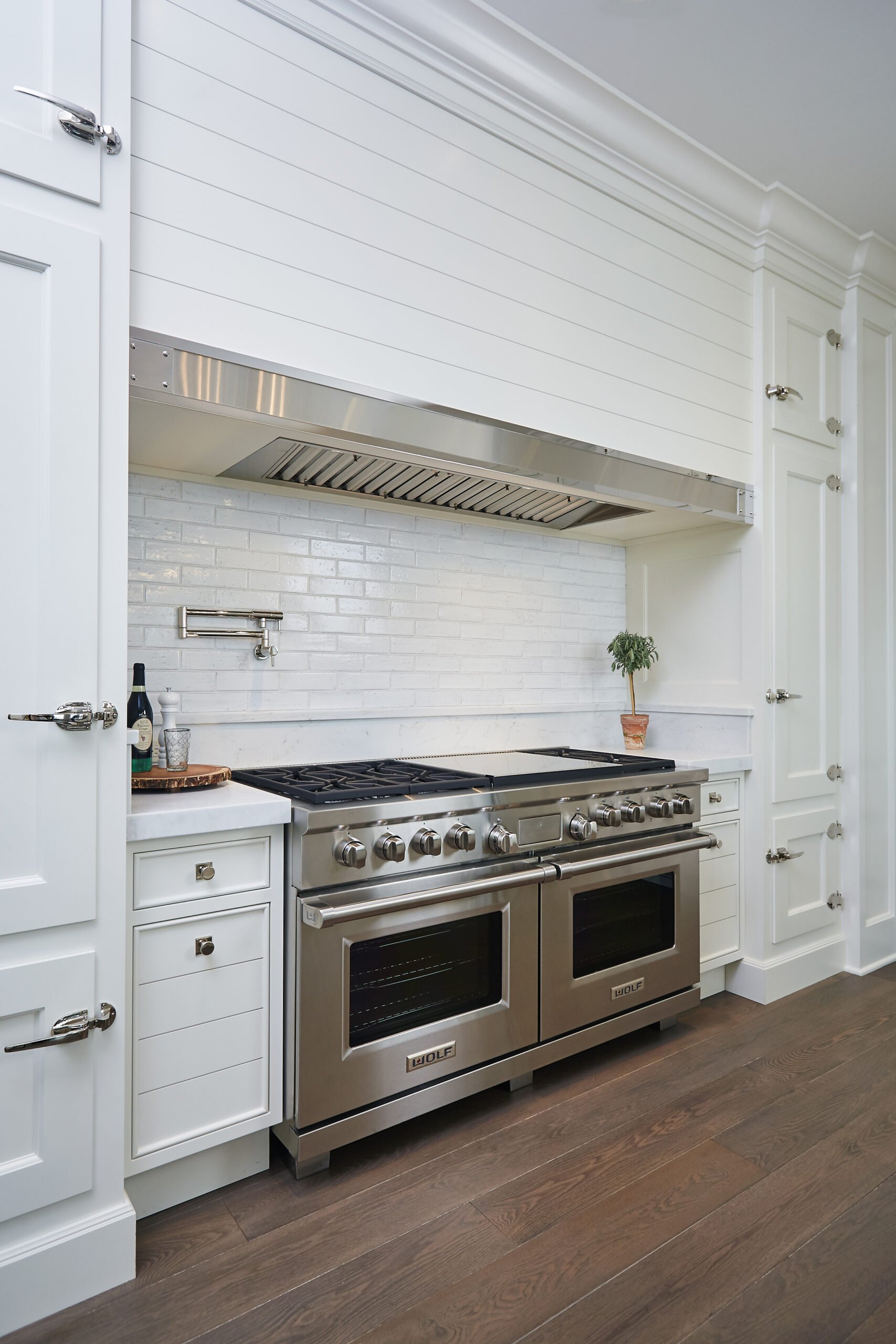 Custom kitchen range with white shiplap hood and stainless steel Wolf appliances