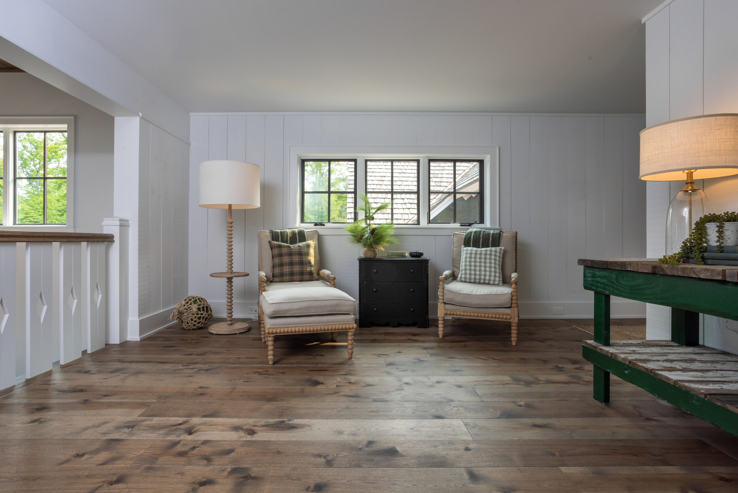 Second-floor sitting area with wood floors, neutral armchairs, and plaid accents.