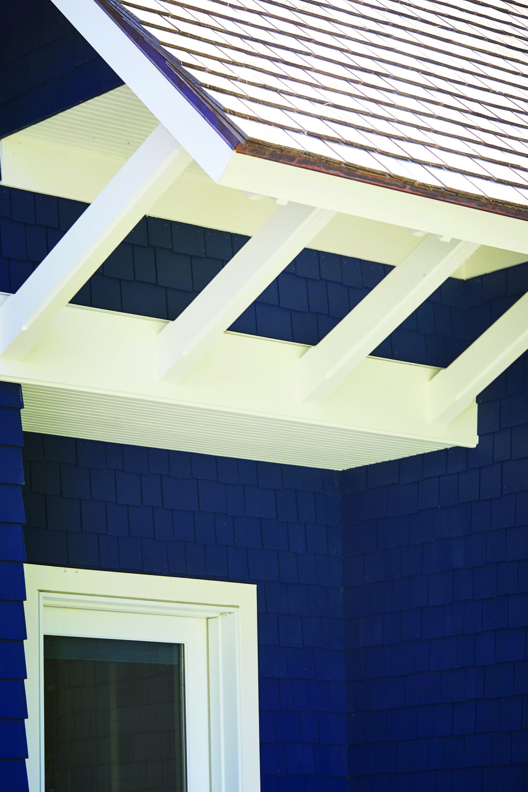 Blue shingle exterior with white eaves and exposed rafter tails