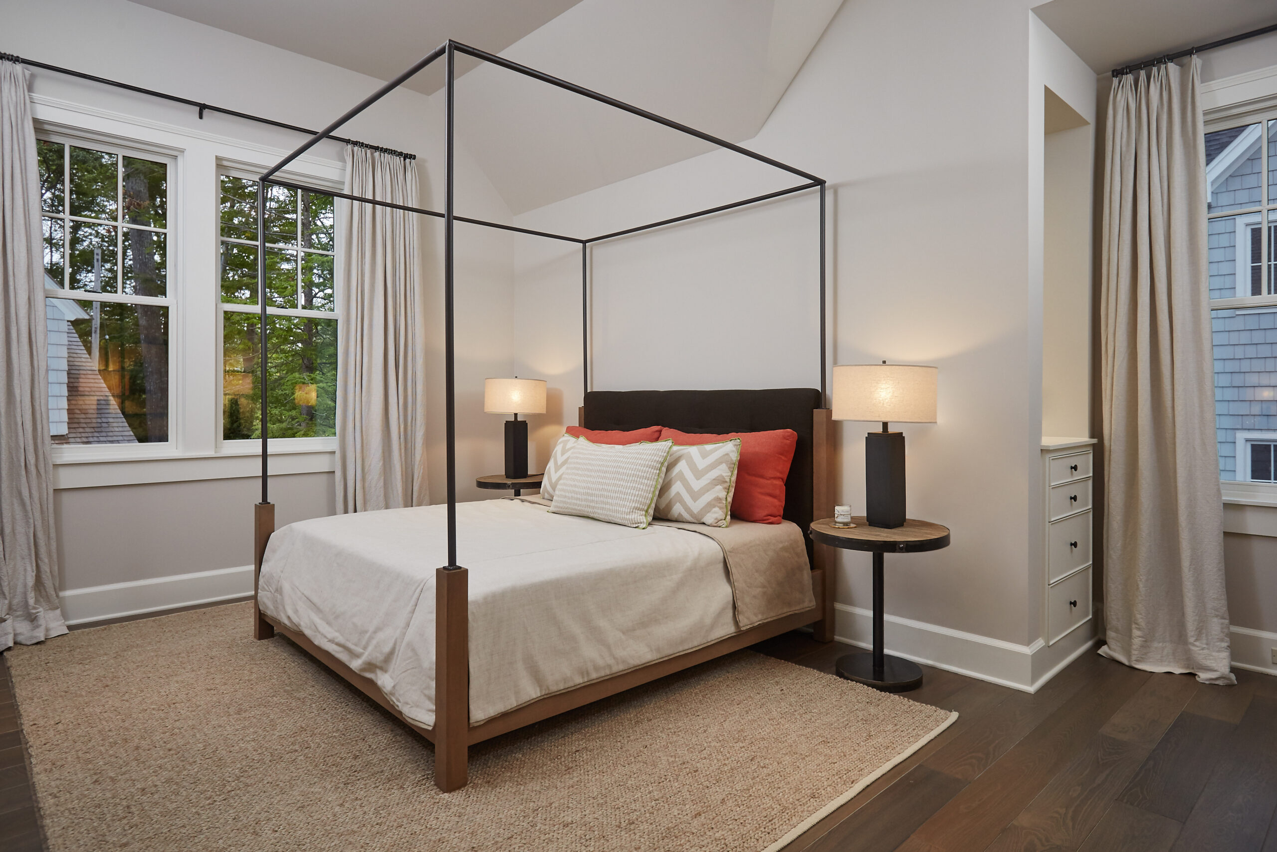 Modern guest bedroom with black metal canopy bed and neutral finishes