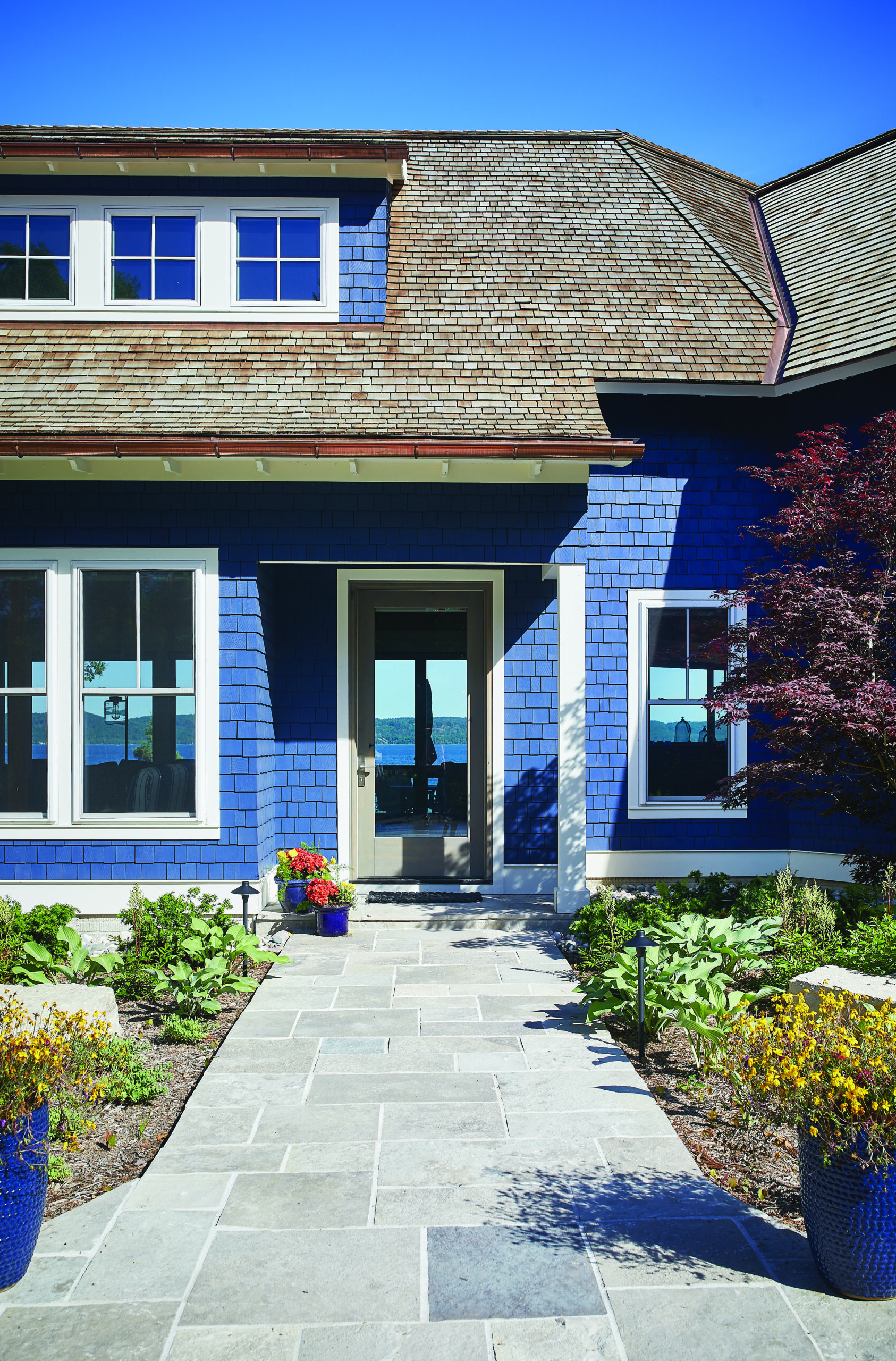 Blue shingle lakeside home entry with stone walkway and glass door