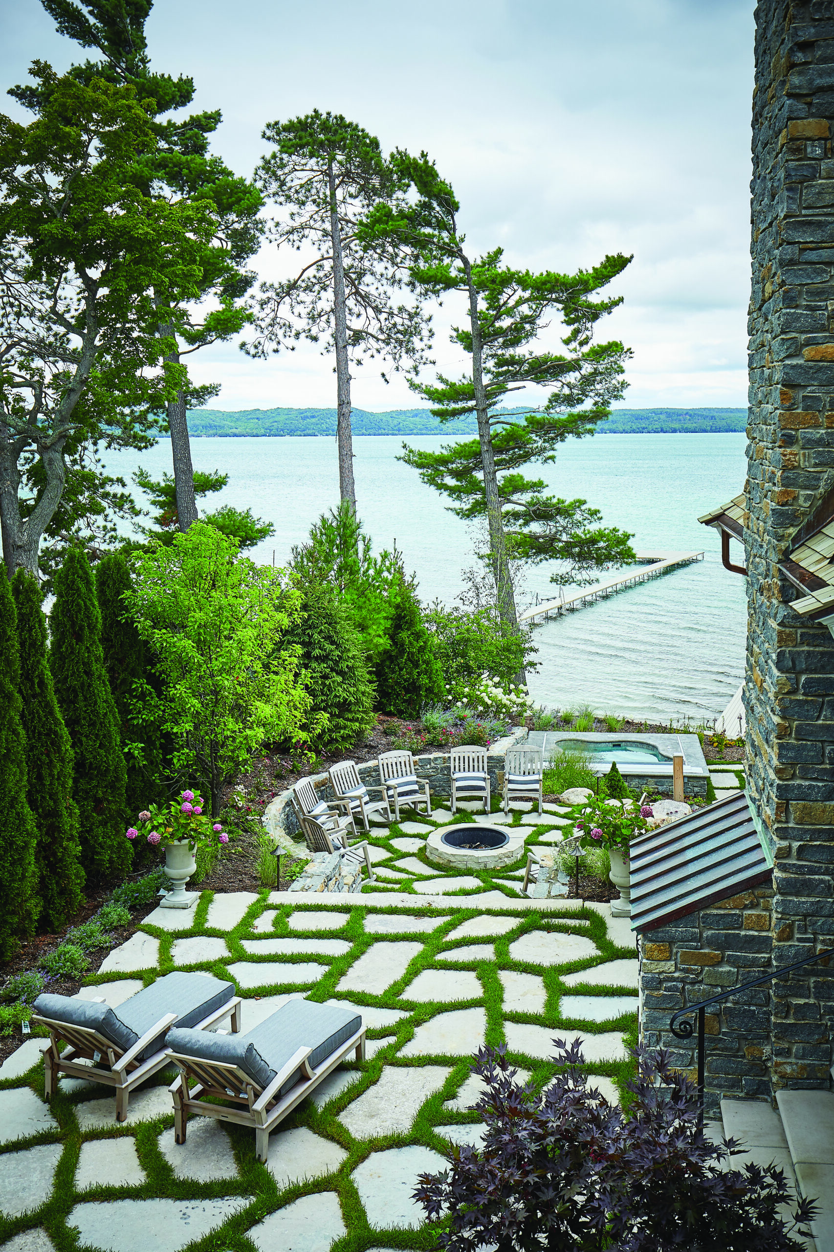 Lakeside stone patio with fire pit and seating at Glen Arbor home