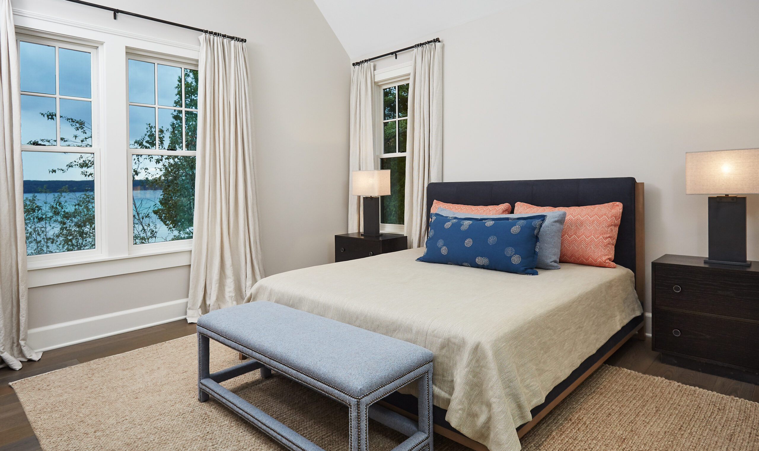 Bright guest bedroom with lake views, neutral bedding, and soft accent pillows