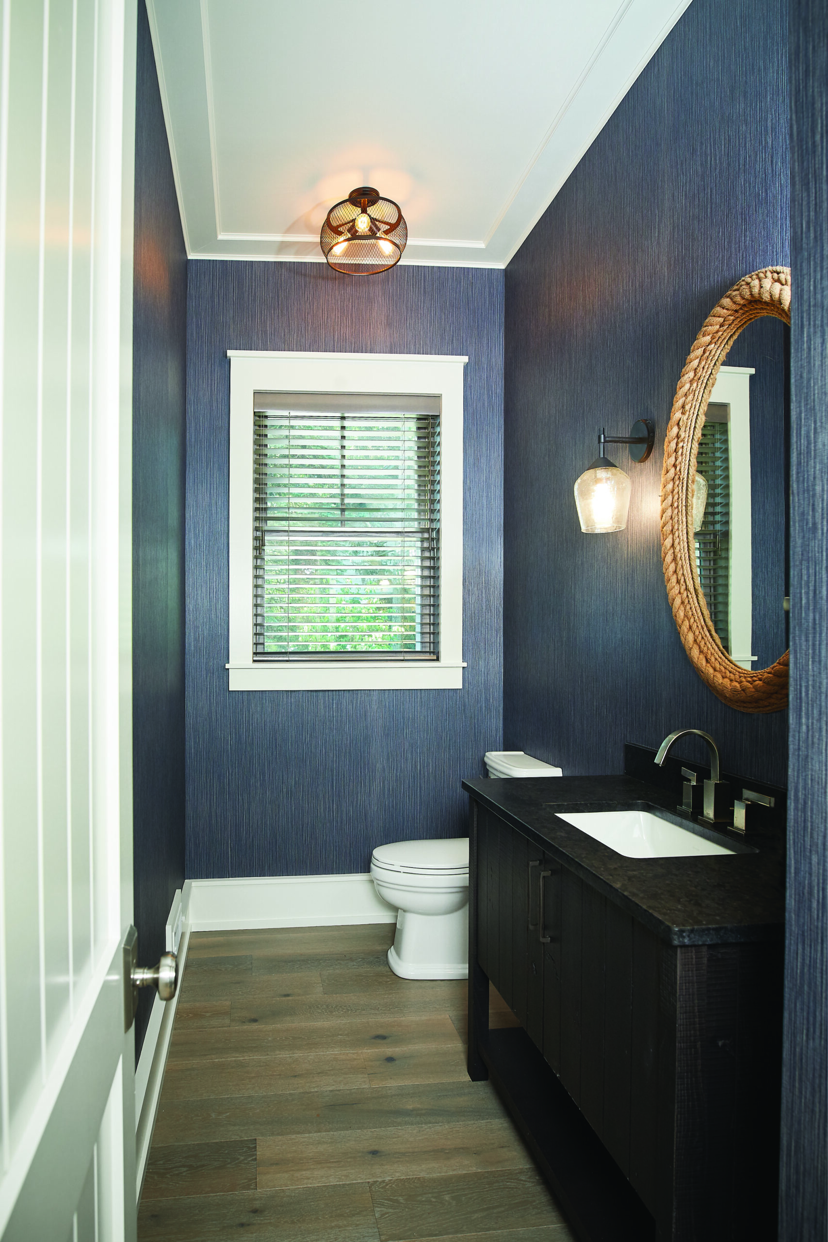 Modern powder room with navy textured walls and rope-framed mirror