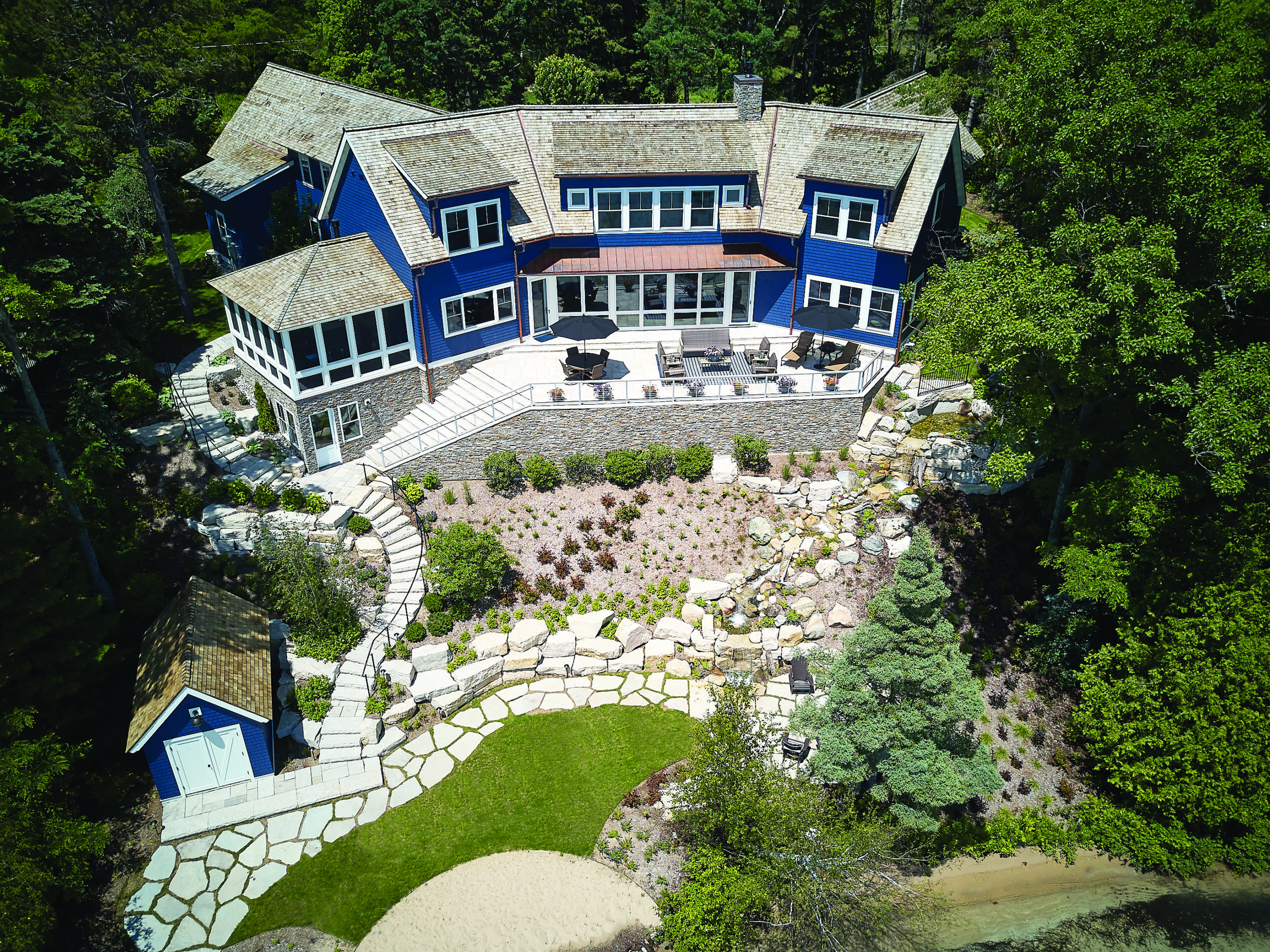 Aerial view of Glen Arbor lakeside home with terraced stone landscaping and expansive patio