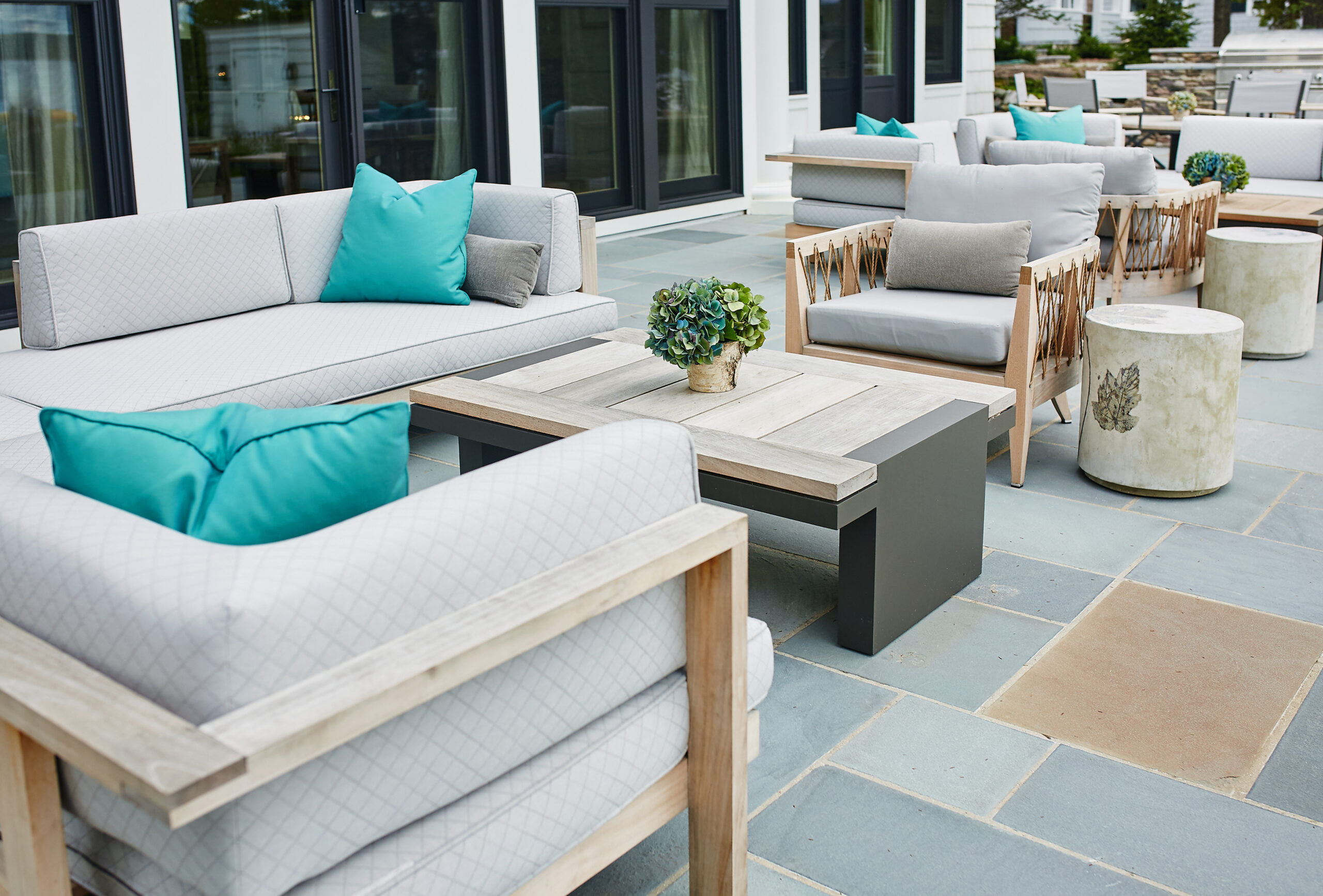 Modern lakeside patio seating with cushioned sofas and teal accent pillows