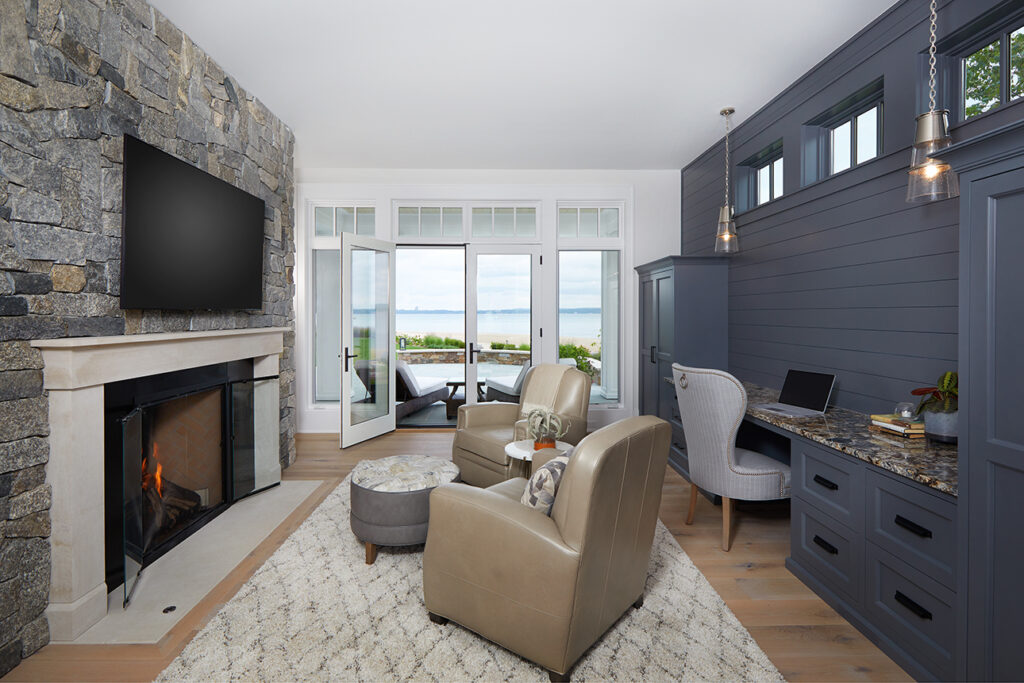 Combination sitting room/home office with stone fireplace, built-in desk, and lake view doors