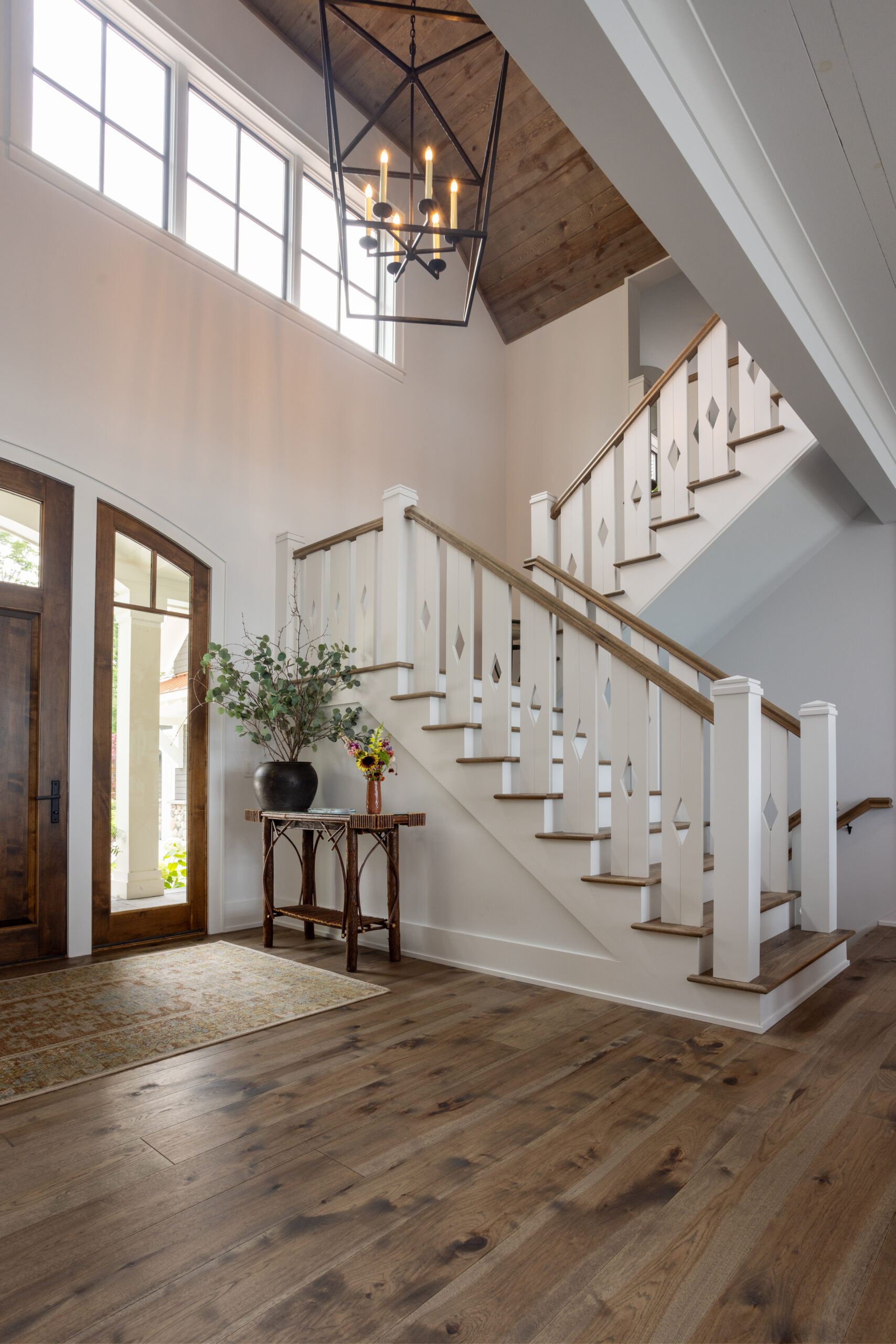 Entryway with custom stair railing and wood ceiling detail