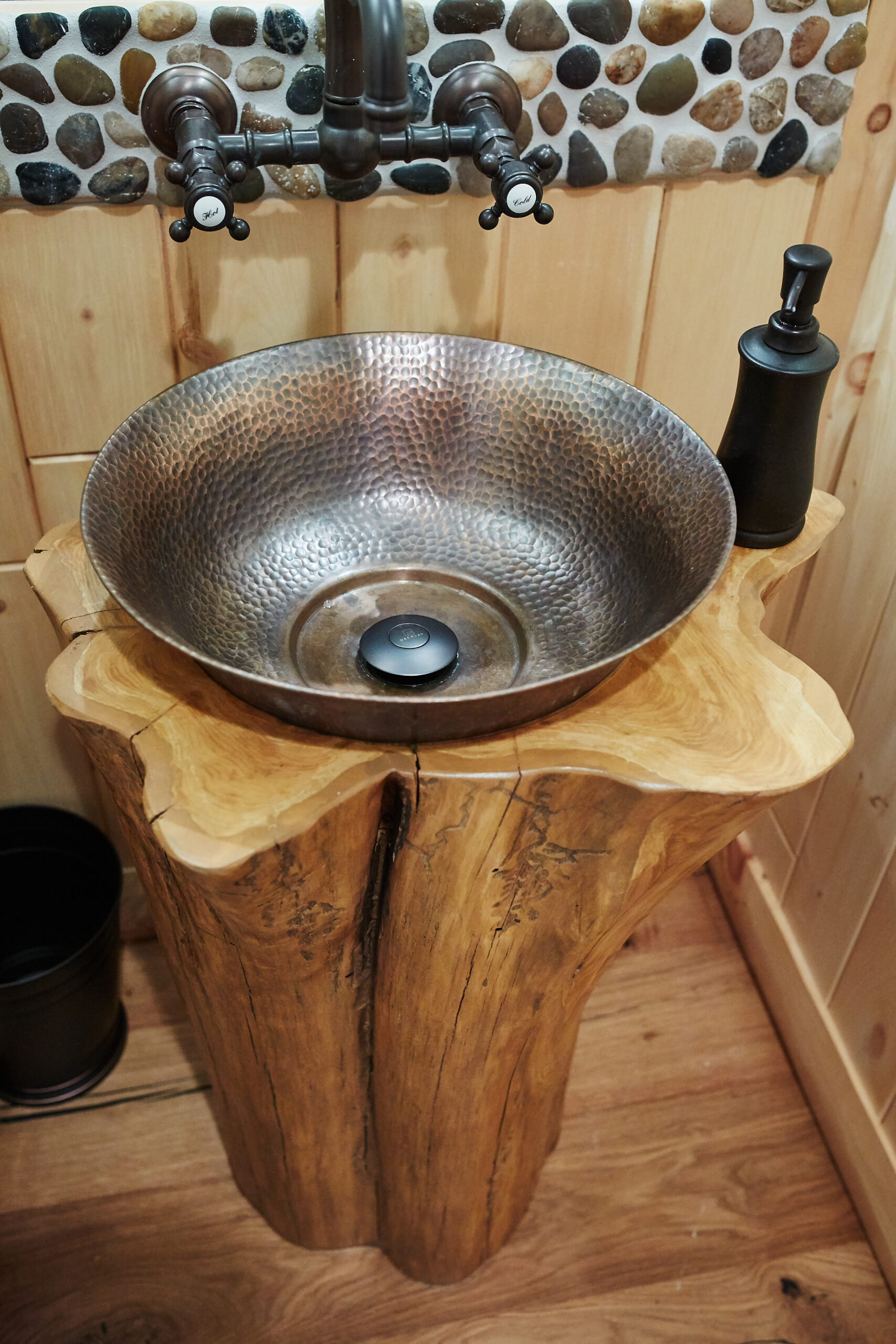 Rustic bathroom sink with hammered metal basin and live-edge wood pedestal