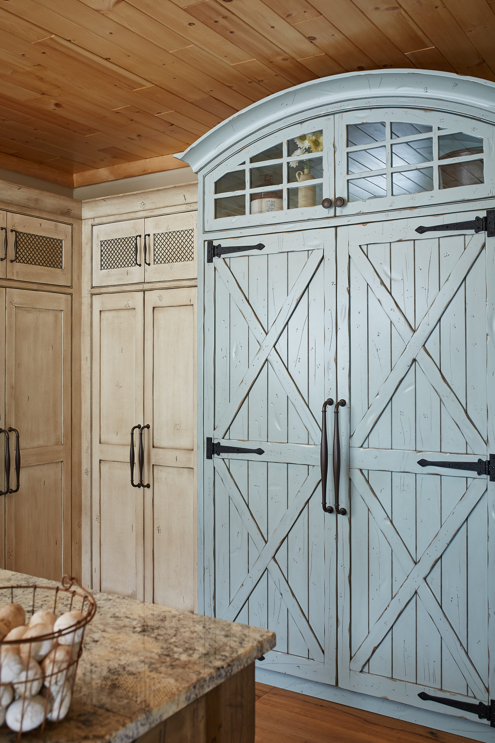 Rustic kitchen cabinetry with light blue barn-style pantry doors