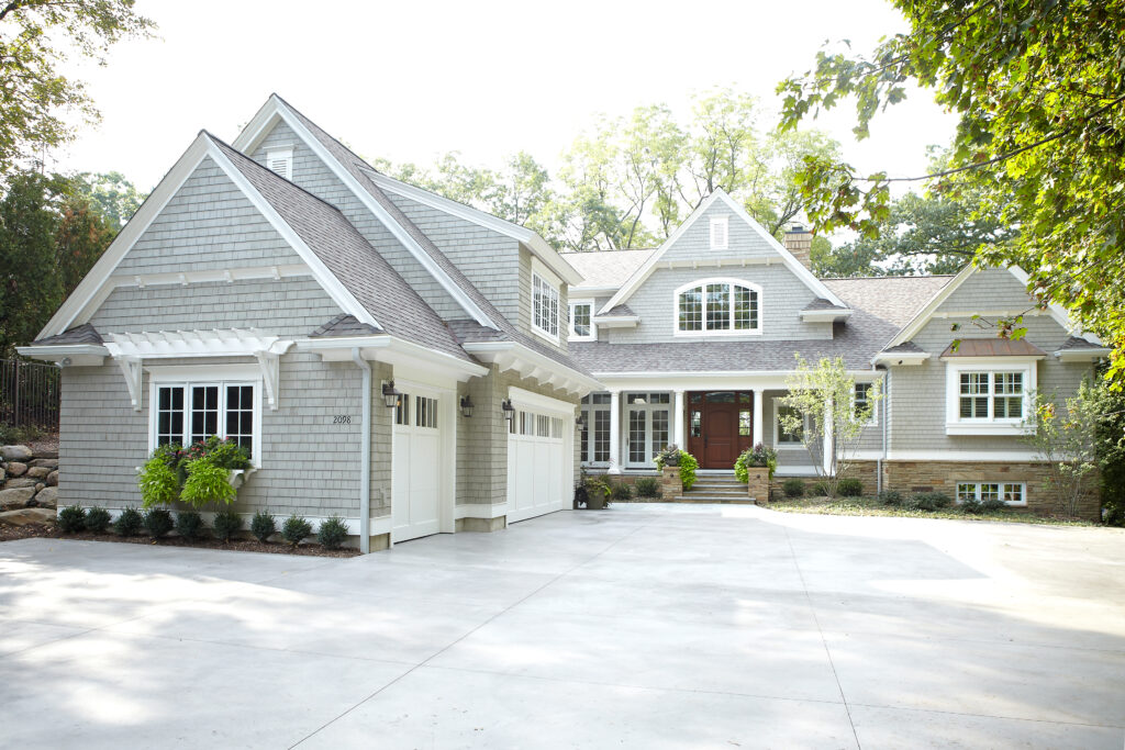 Cottage-style home with gray shingle siding, gabled rooflines, and spacious front driveway