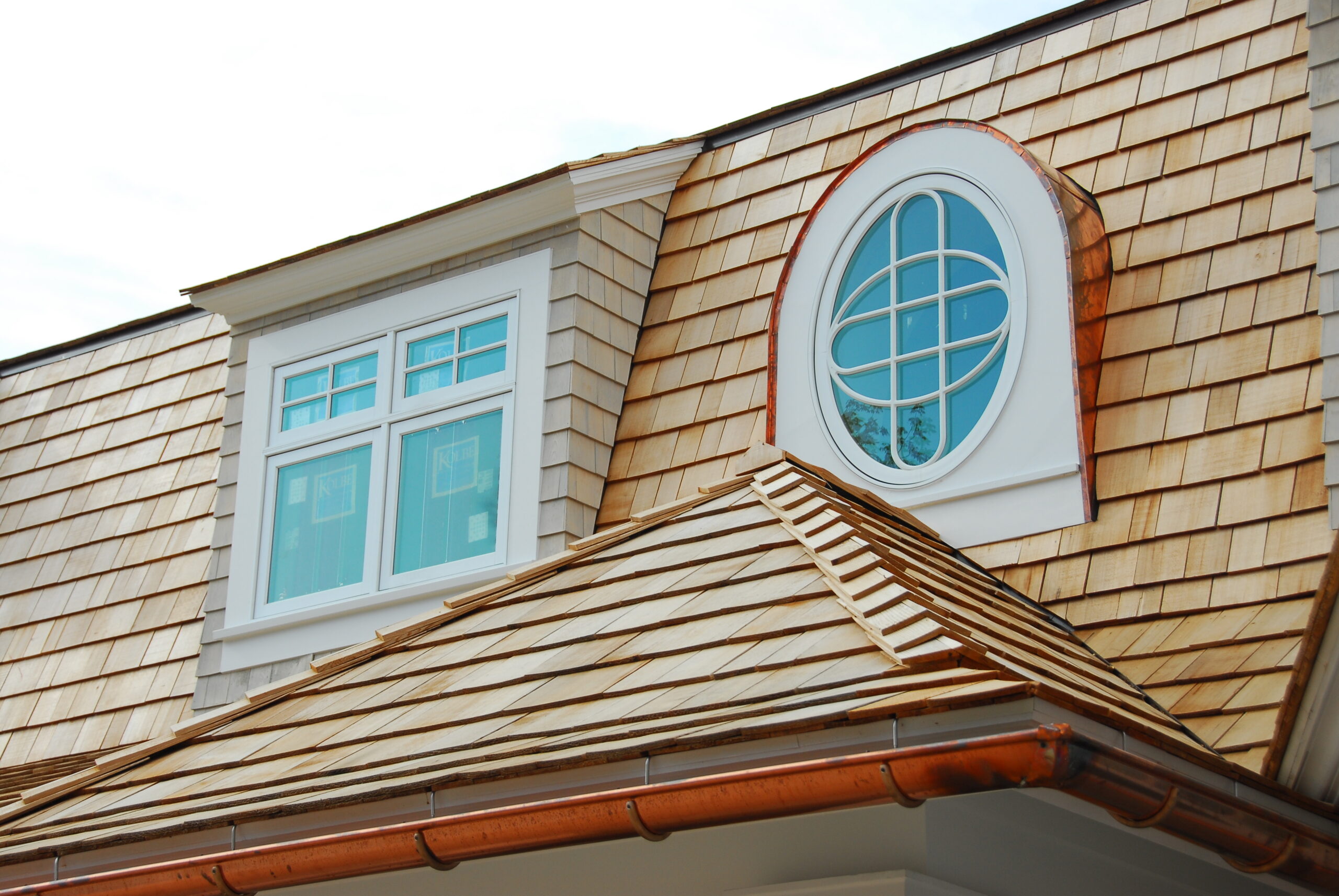 Cedar shake roof with oval dormer window and copper gutter