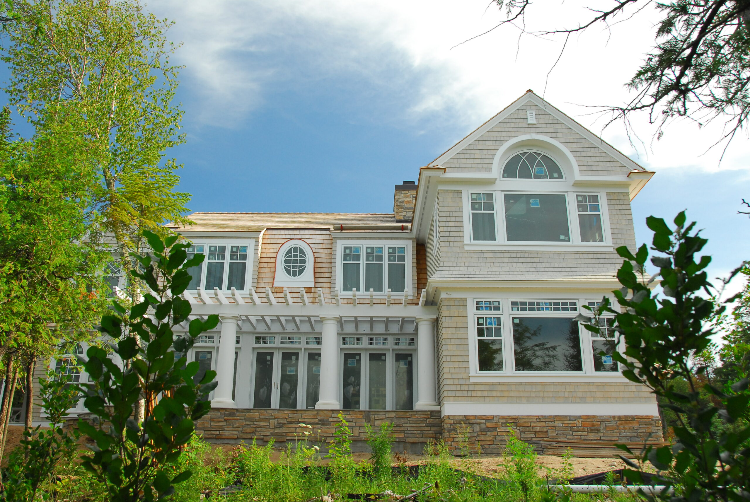 Lakeside cedar shake home exterior with pergola porch and large windows