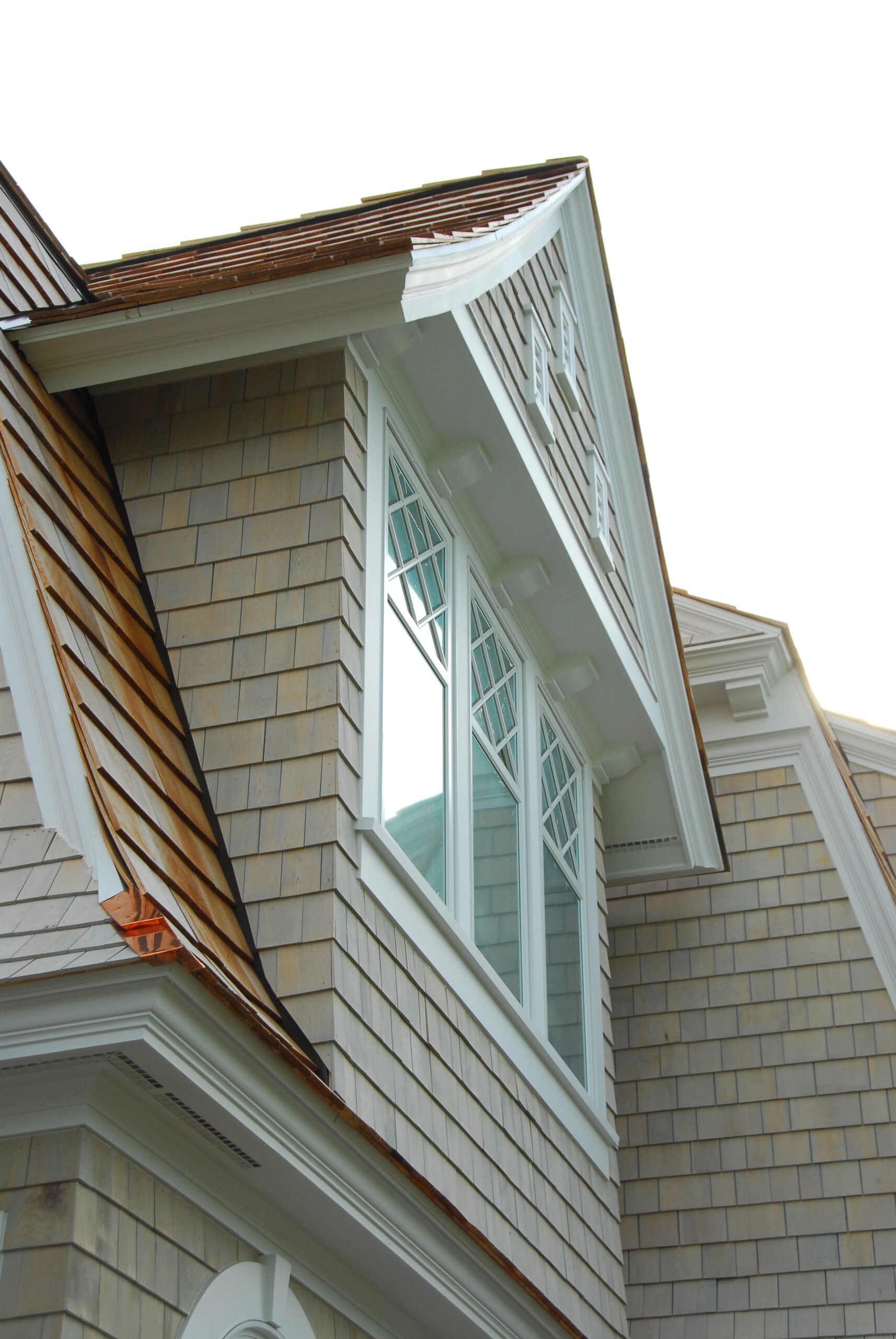 Exterior detail of cedar shake home with white trim and decorative window muntins