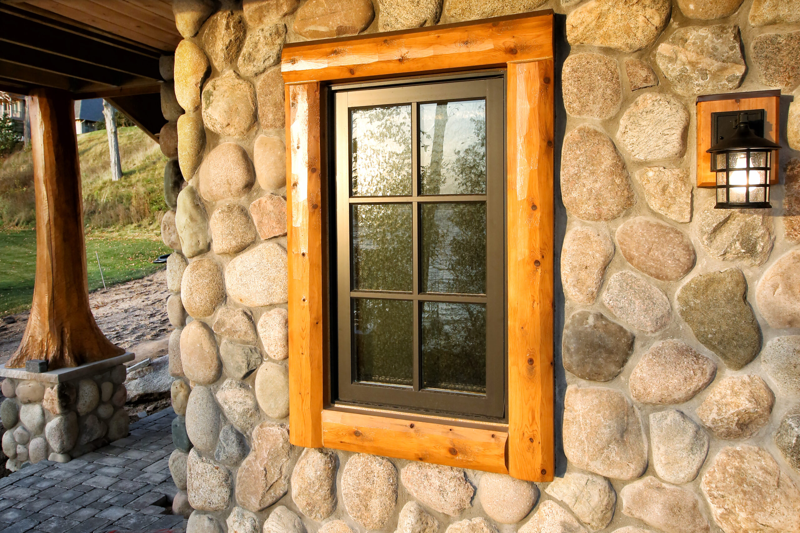 Lake Charlevoix custom home exterior with fieldstone wall, natural wood window trim, and craftsman-style lantern