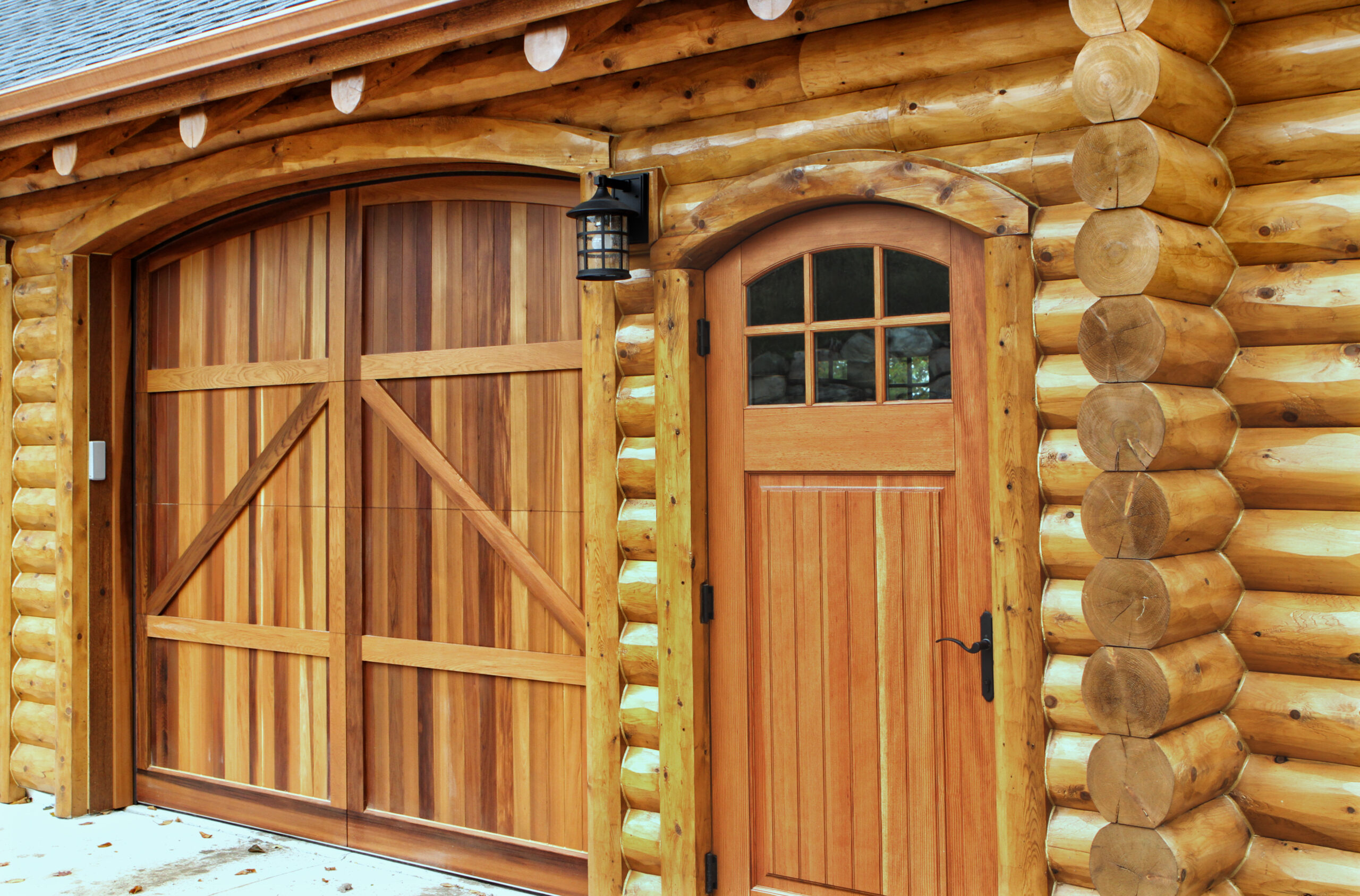Custom log garage and entry door with arched cedar panels on Lake Charlevoix log home