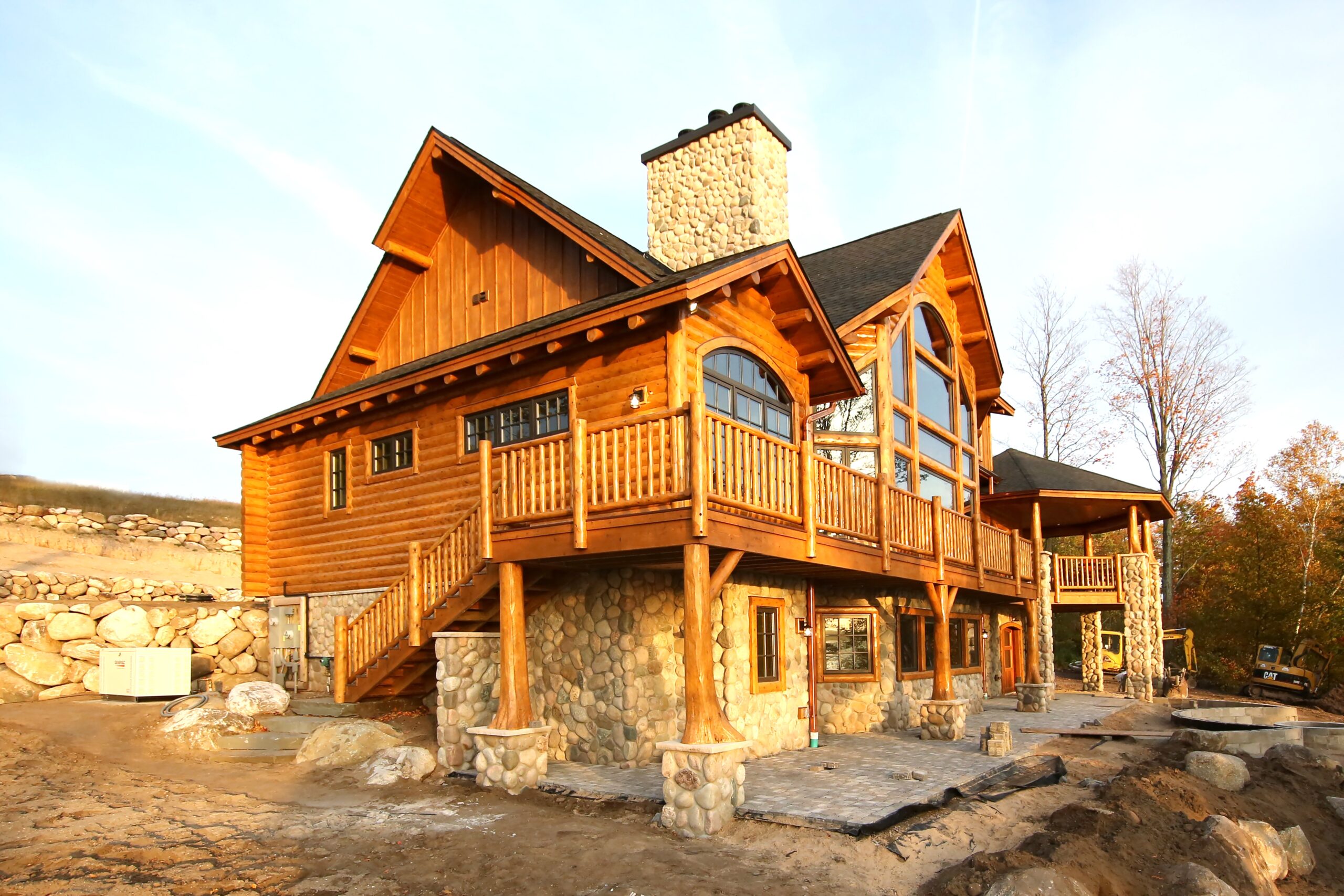 Custom log home in Lake Charlevoix with fieldstone foundation, lakeside deck, and large arched windows