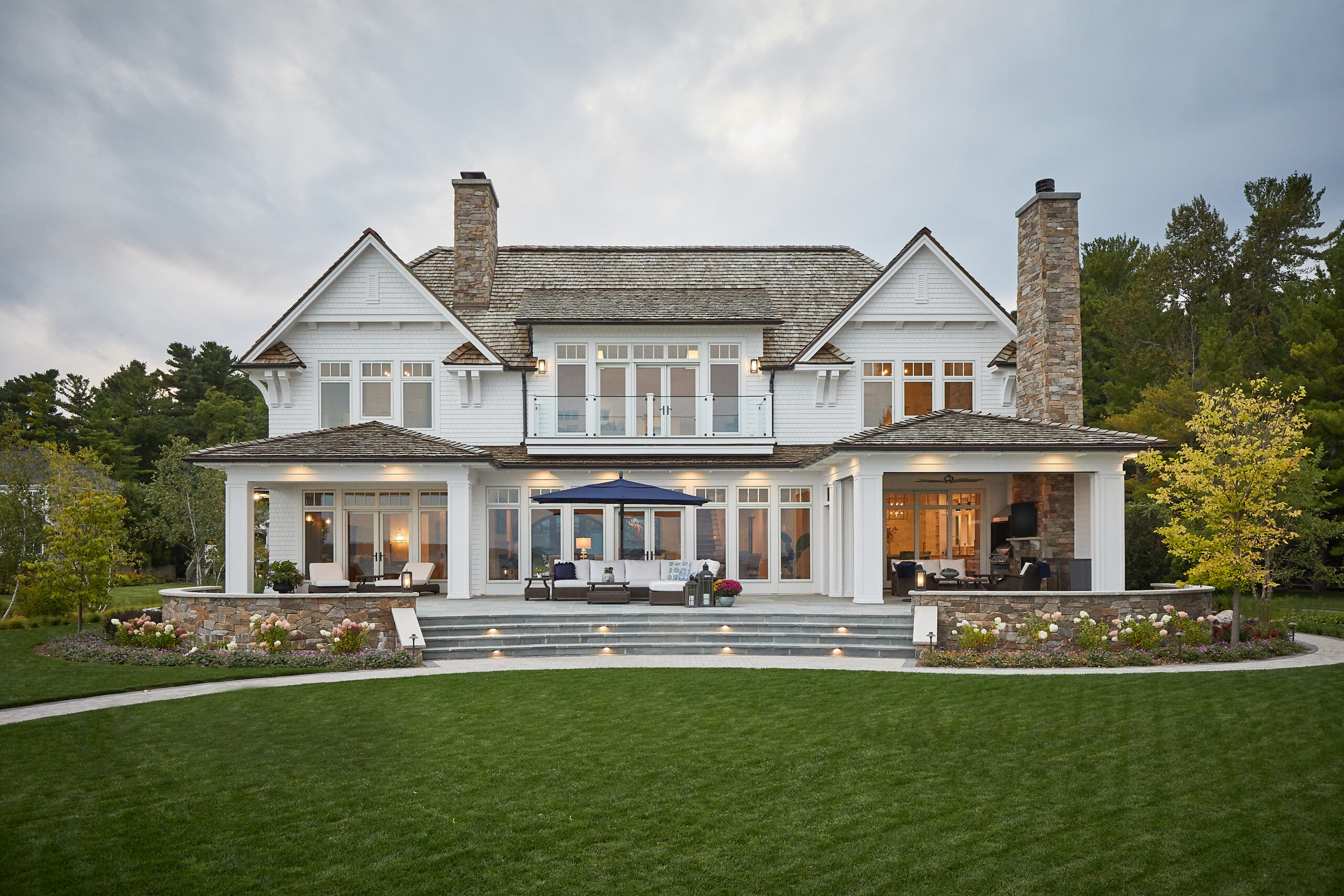 Back exterior view of a luxury home with patio, balconies, and landscaped yard.
