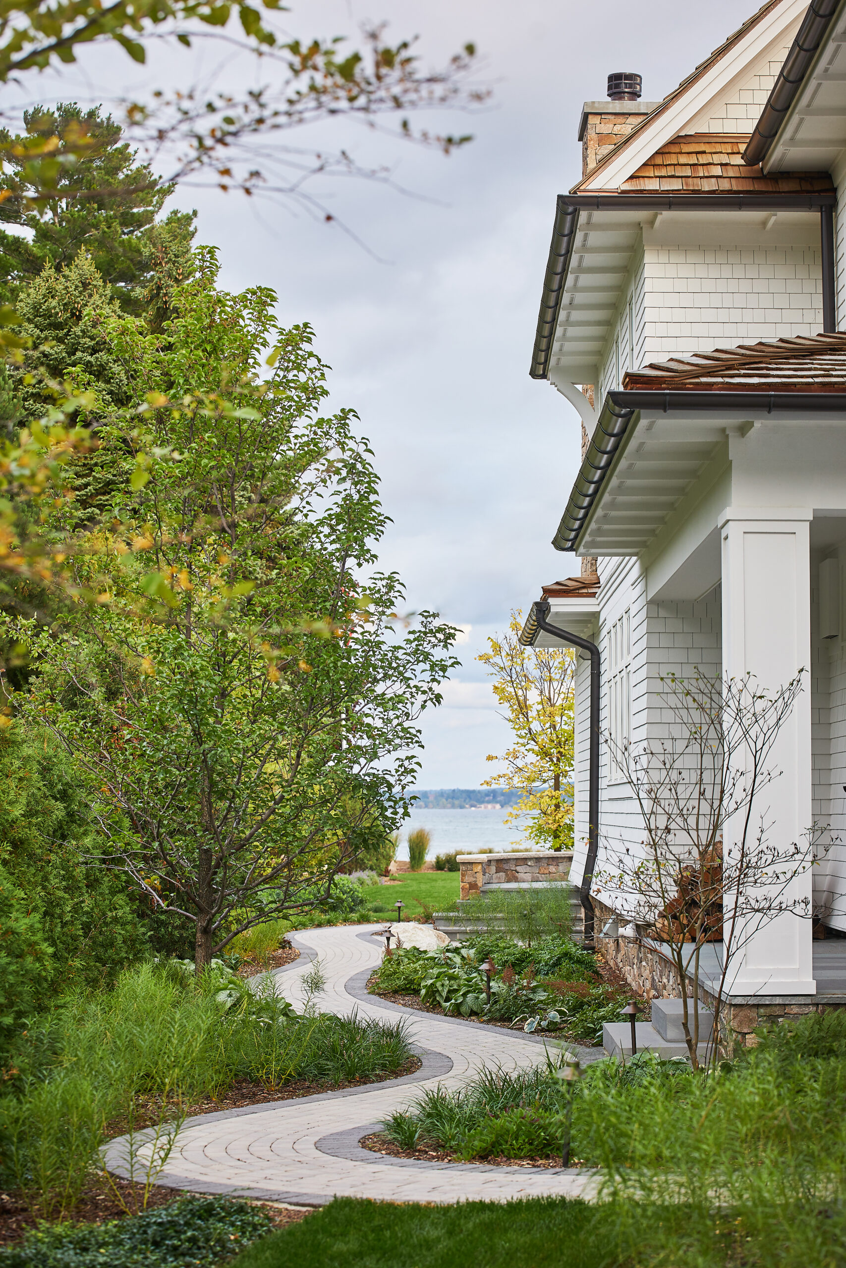 Curved stone walkway through lush landscaping leading to a lakefront view.