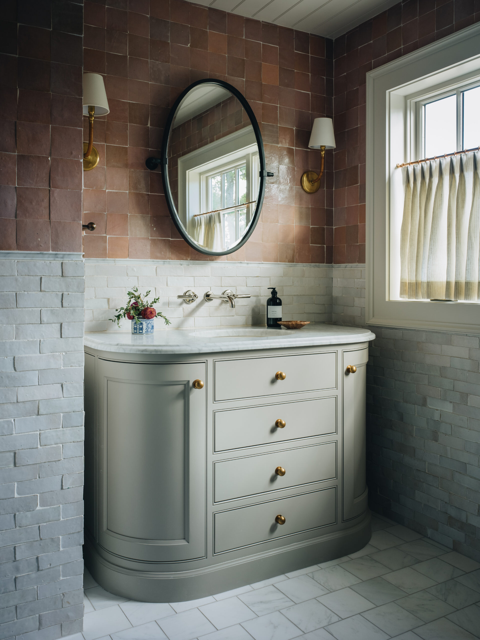 Elegant guest bathroom with curved vanity, gold hardware, and two-tone zellige tile walls.