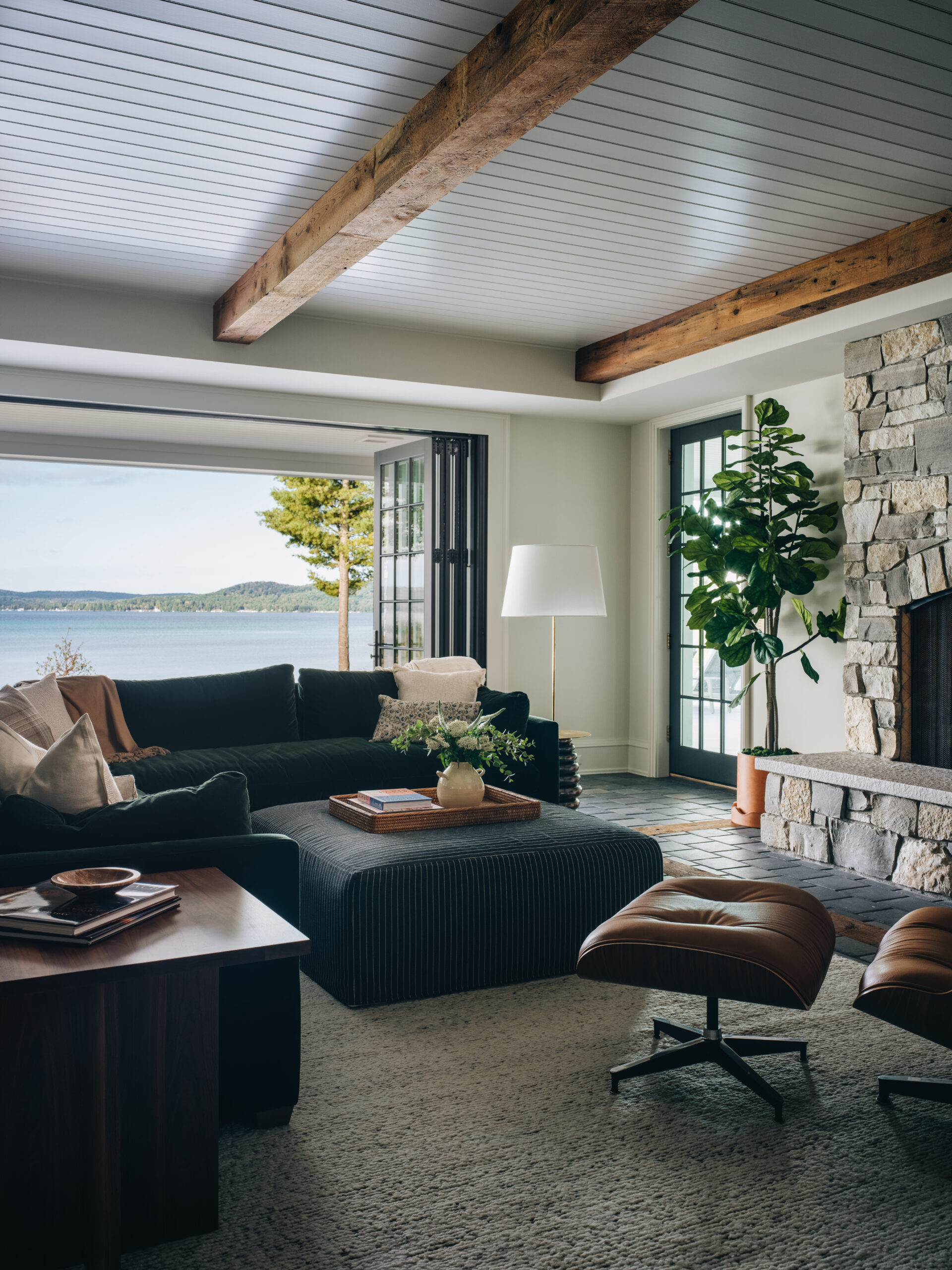 Lakeview living room in Glen Lake custom home with exposed beams, stone fireplace, and folding glass doors