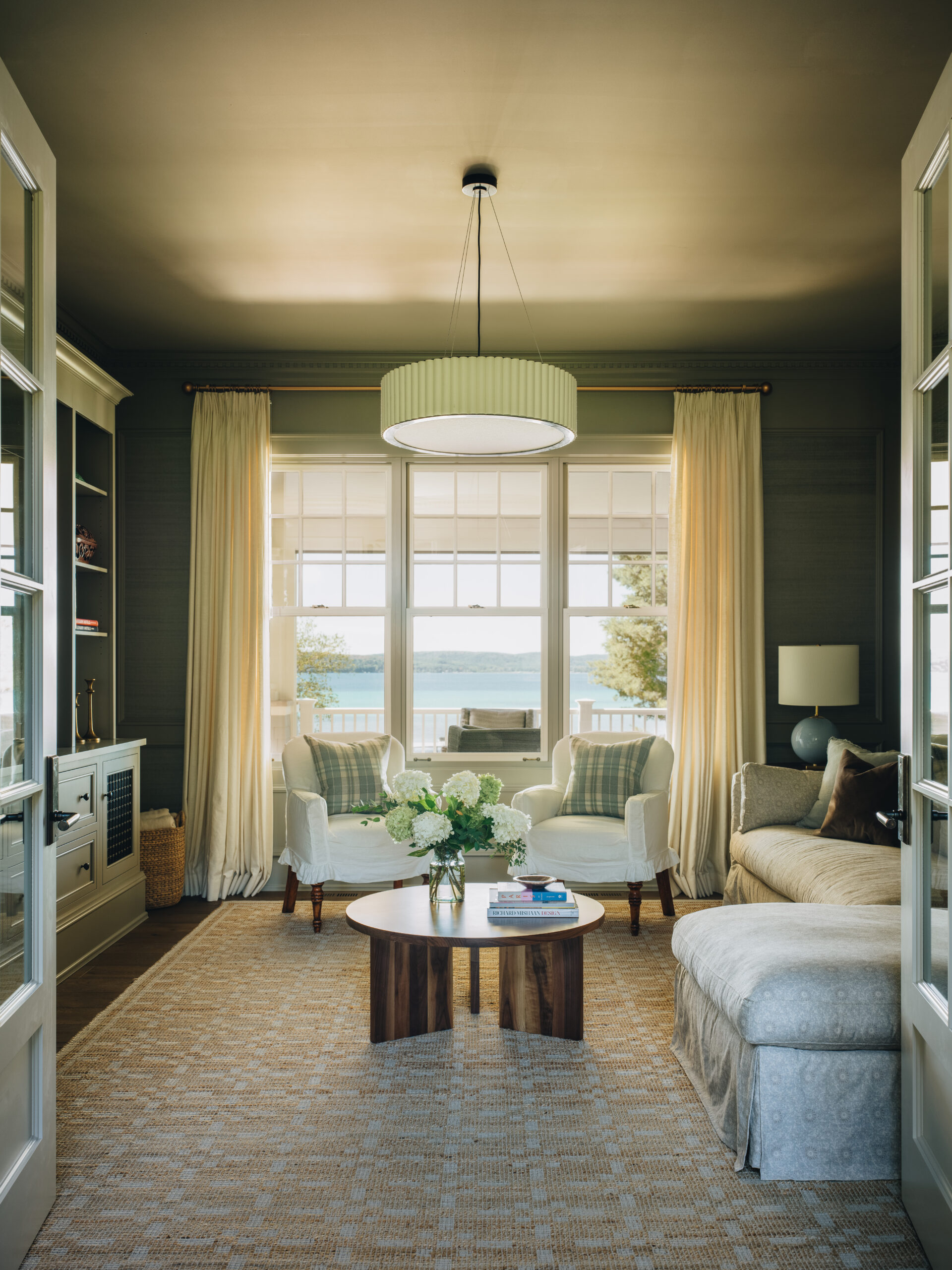 Lakeview sitting room in Glen Lake custom cottage with French doors, tailored upholstery, and panoramic windows