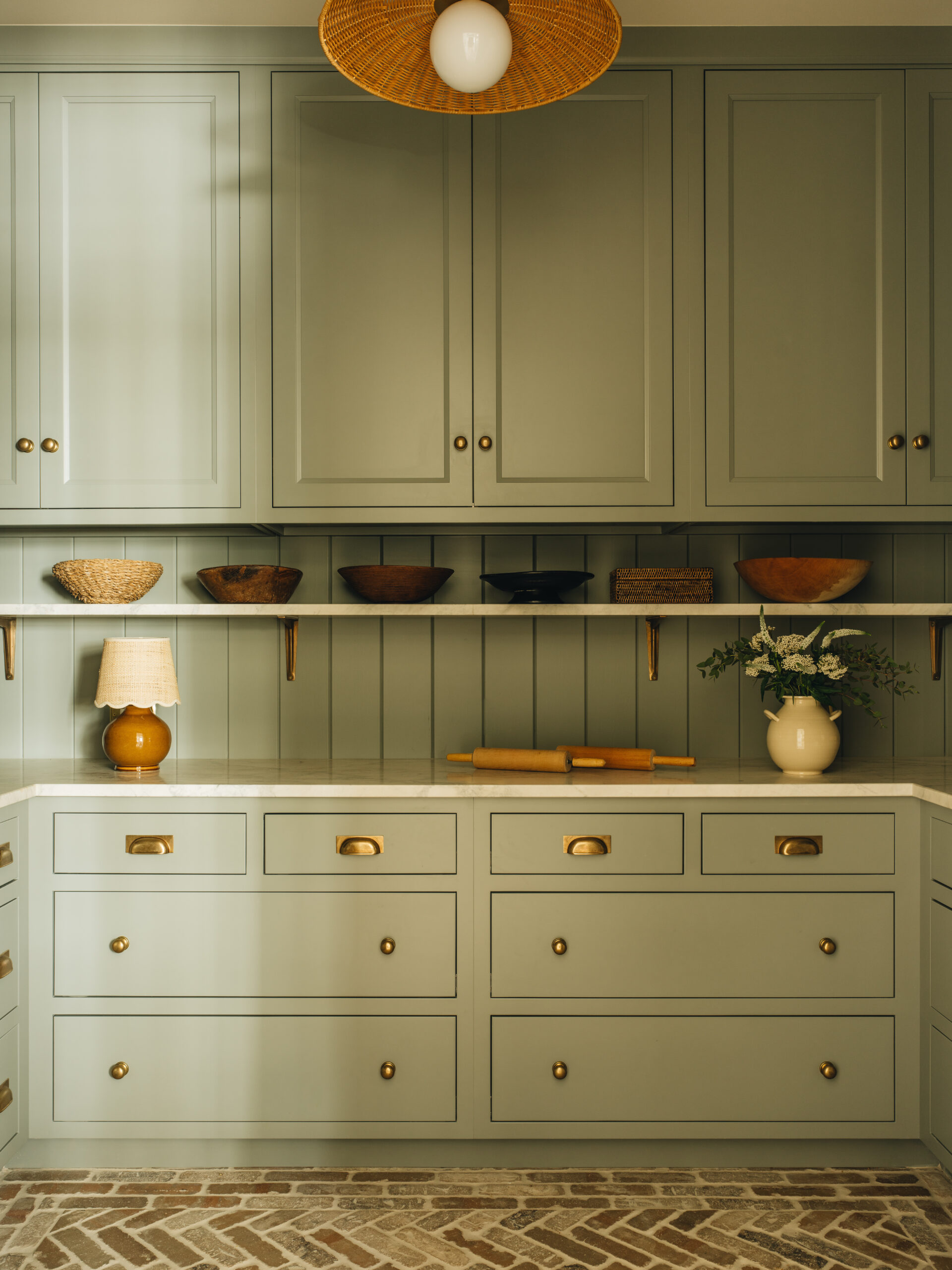 Custom butler’s pantry with green cabinetry, marble counters, and herringbone brick floor in Glen Lake home