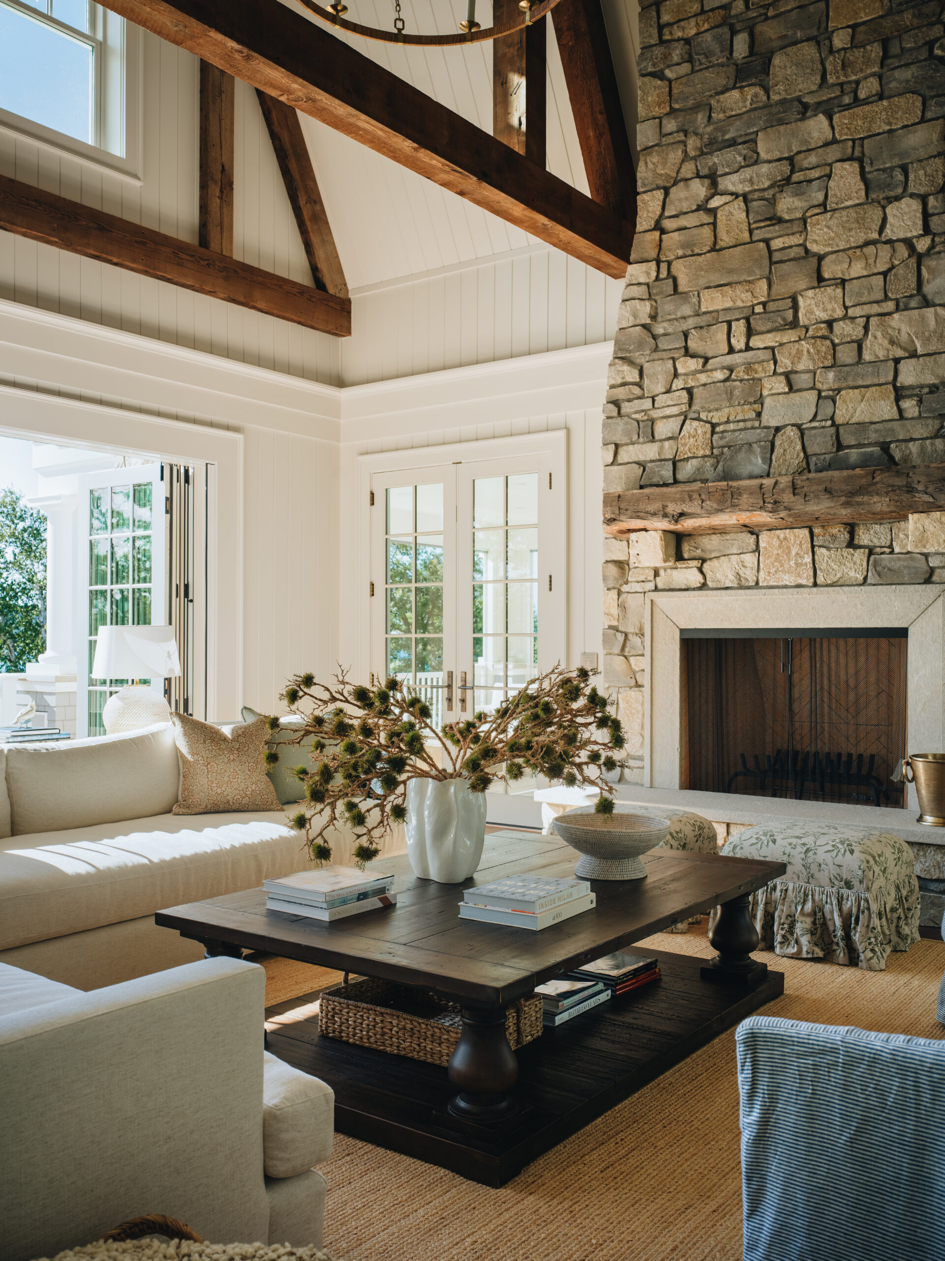 Living room with vaulted ceiling, stone fireplace, and rustic beams in Glen Lake custom home