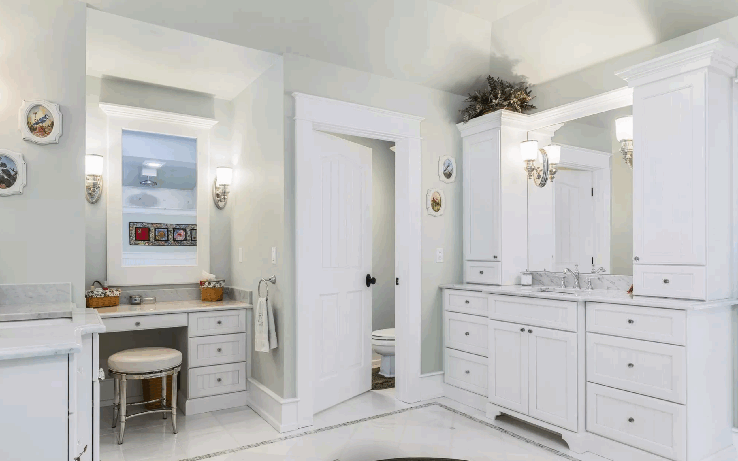 Bright white primary bathroom with double vanity, marble countertops, and built-in makeup station